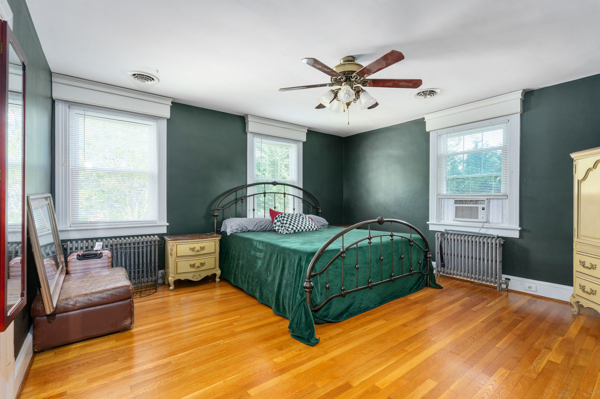 Master bedroom with dark green accent walls and hardwood floors