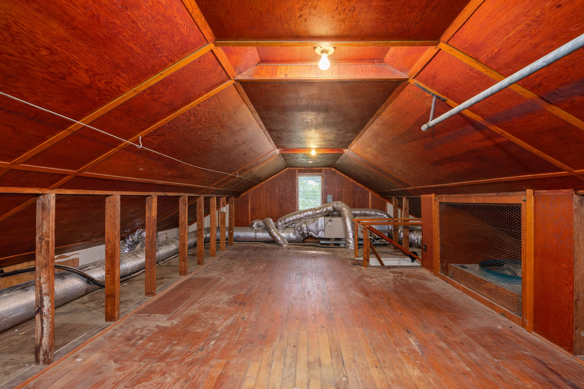 Unfinished attic with exposed rafters and plank flooring