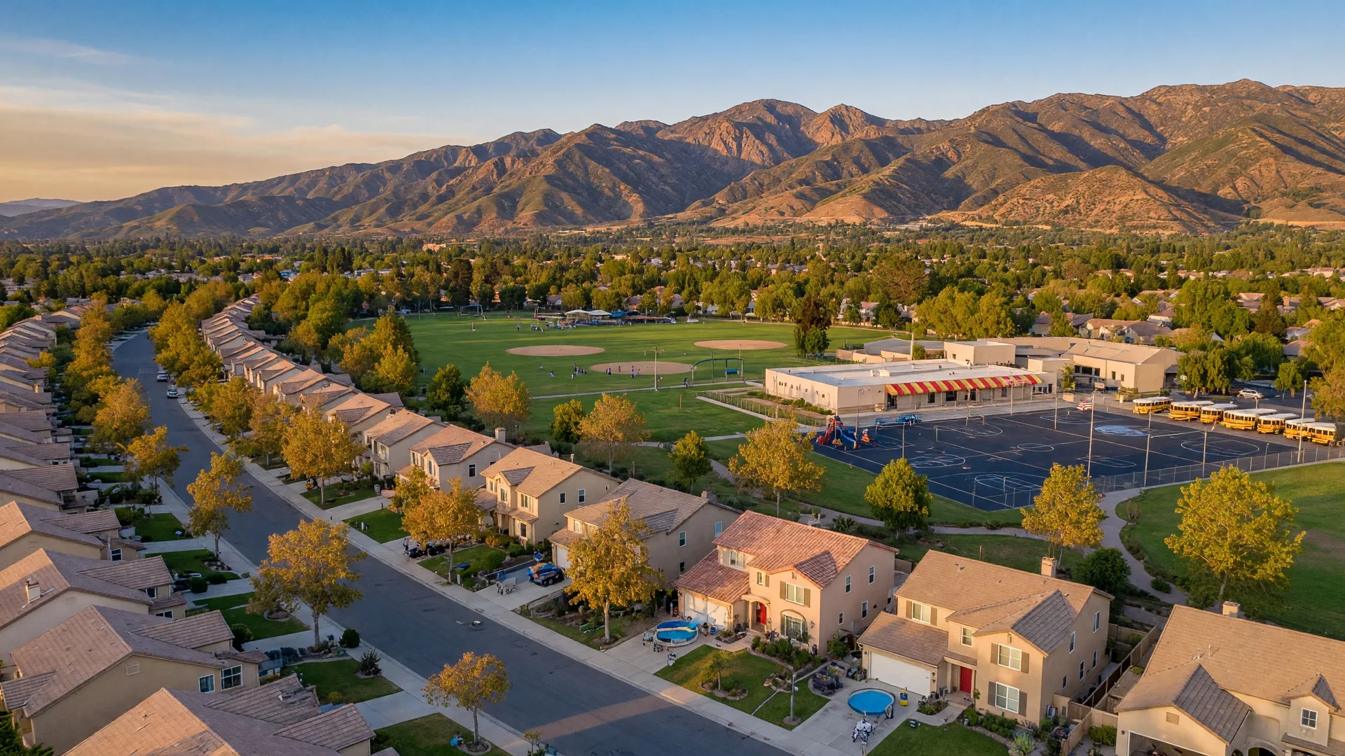 Aerial view of suburban Santa Clarita Valley neighborhoods with tree-lined streets and mountain backdrop