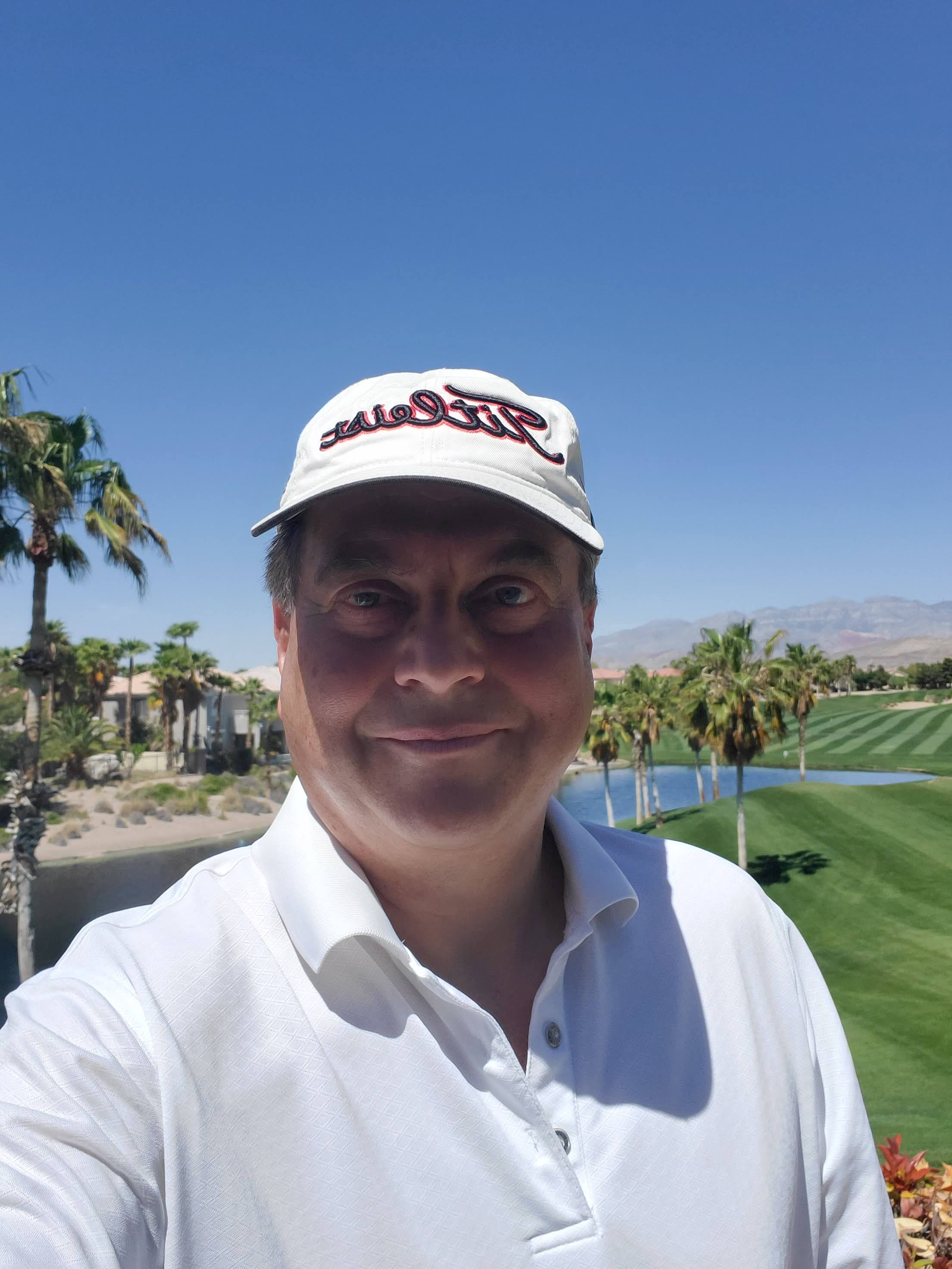 Martin Guaglione in a purple polo on a patio with water features and palm trees at a golf course
