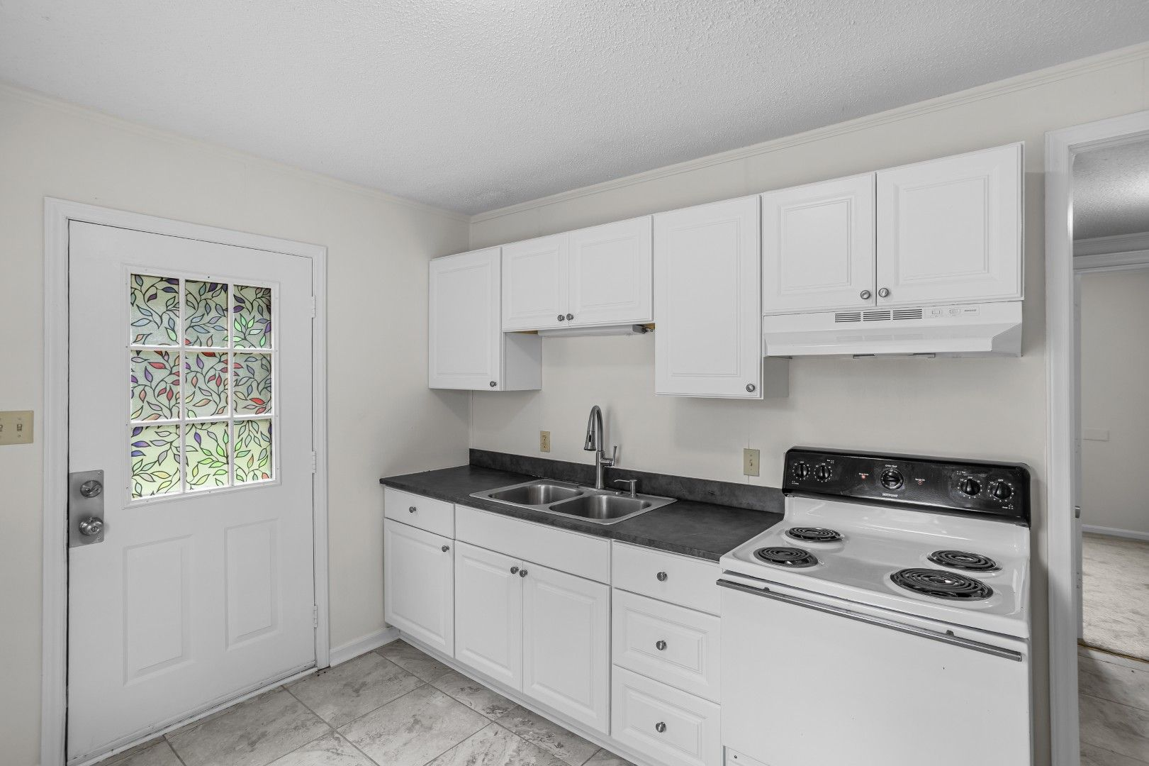 Updated kitchen with white shaker cabinets and dark countertops
