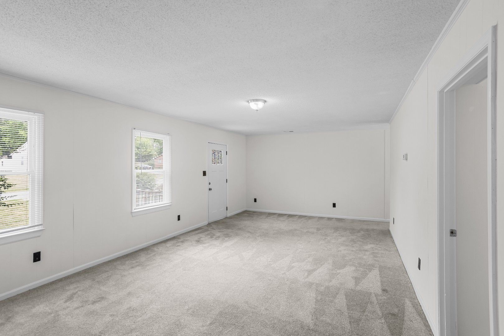 Vacant living room with neutral carpet and white walls