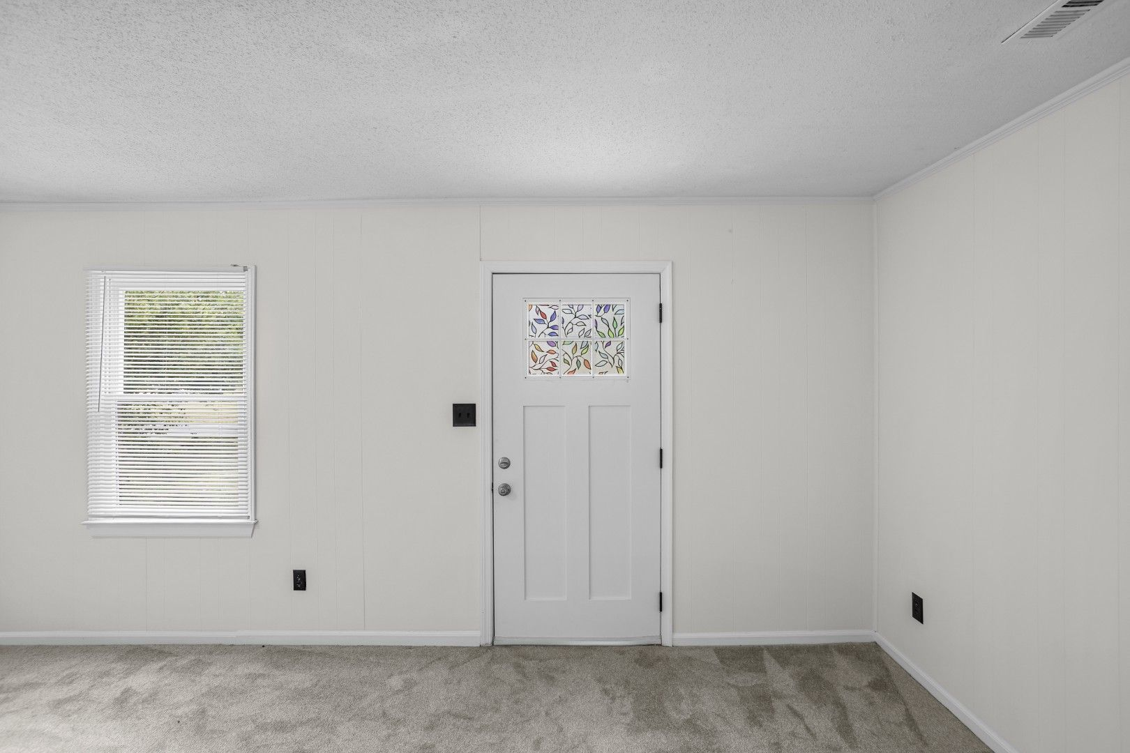 Front entry with stained glass door and grey carpet
