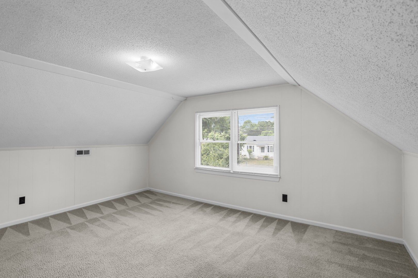 Upper-level bedroom with sloped ceiling and natural light