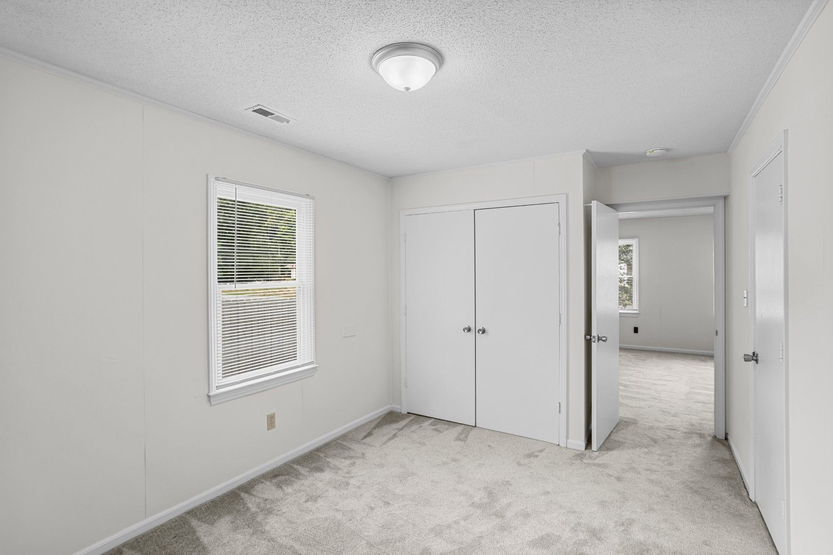 Main-level secondary bedroom with new carpet, white walls, and natural light