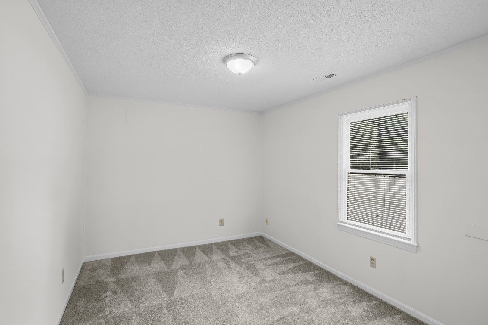 Main-level bedroom with fresh carpet, corner windows, and neutral finish
