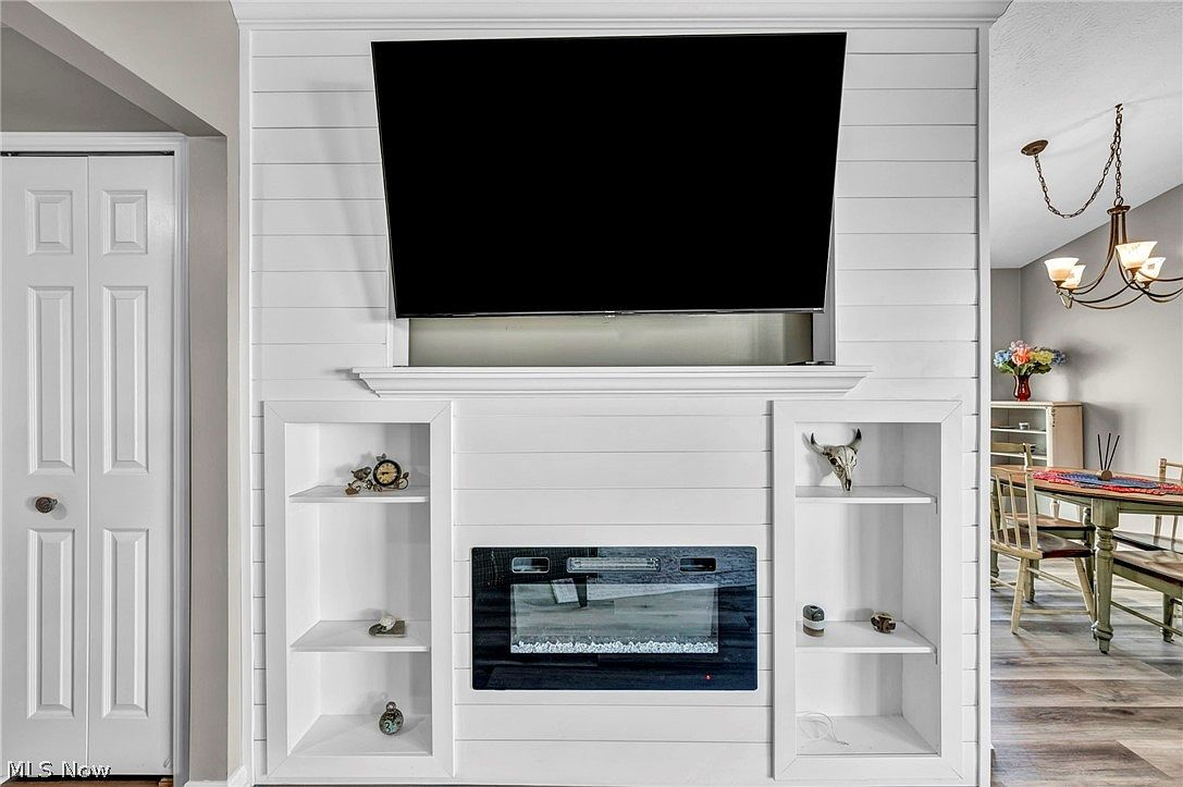 White shiplap accent wall with built-in shelving and electric fireplace