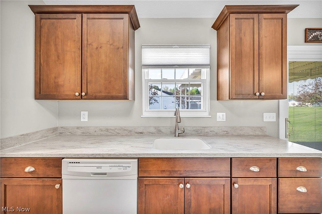 Kitchen sink and counter area with wood cabinetry and daylight