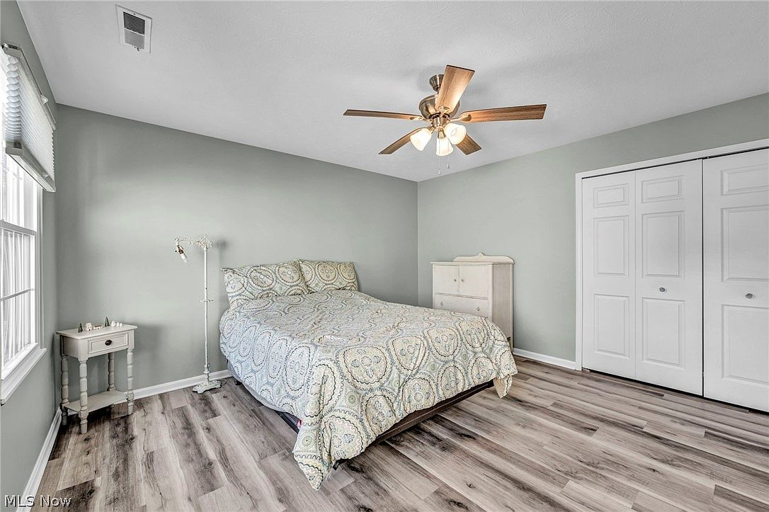 Bedroom with gray walls, wood-look flooring, and natural daylight