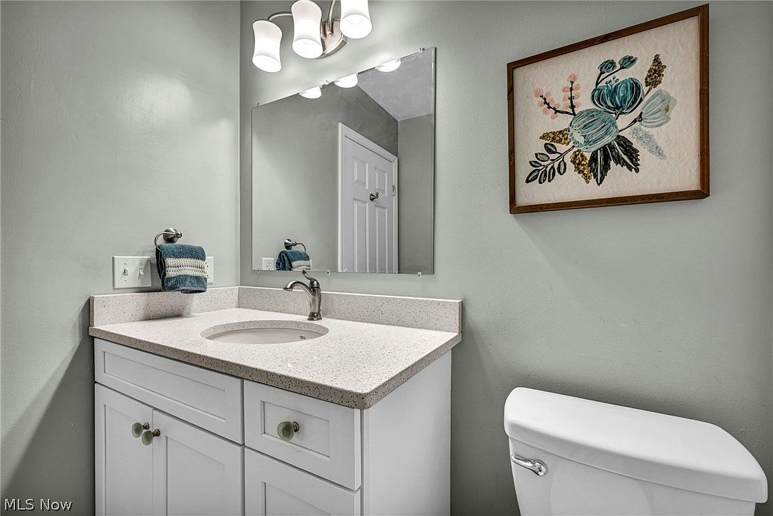 Bathroom with white shaker vanity and speckled quartz countertop