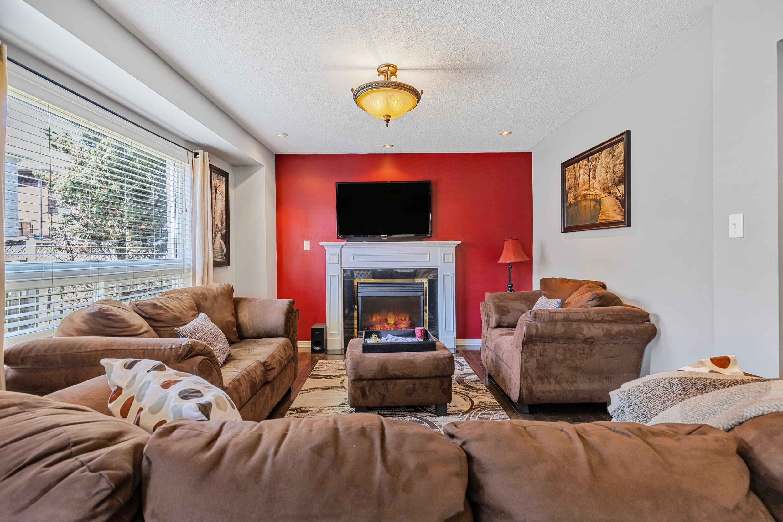 Living room with red accent wall and white fireplace mantel