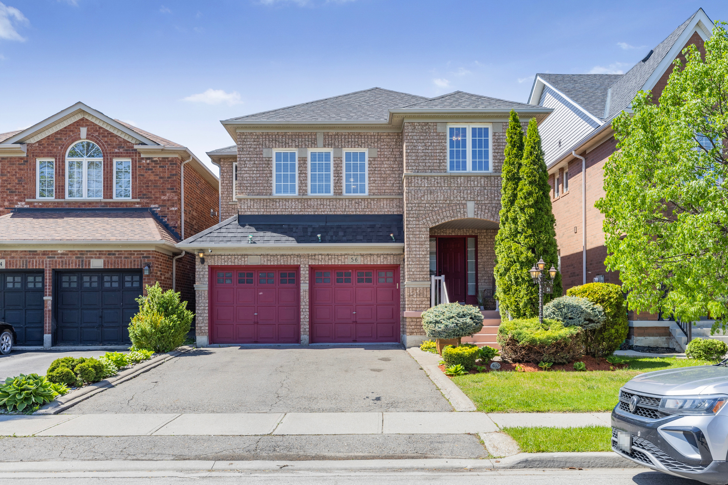 Two-storey home exterior with red garage doors and blue sky