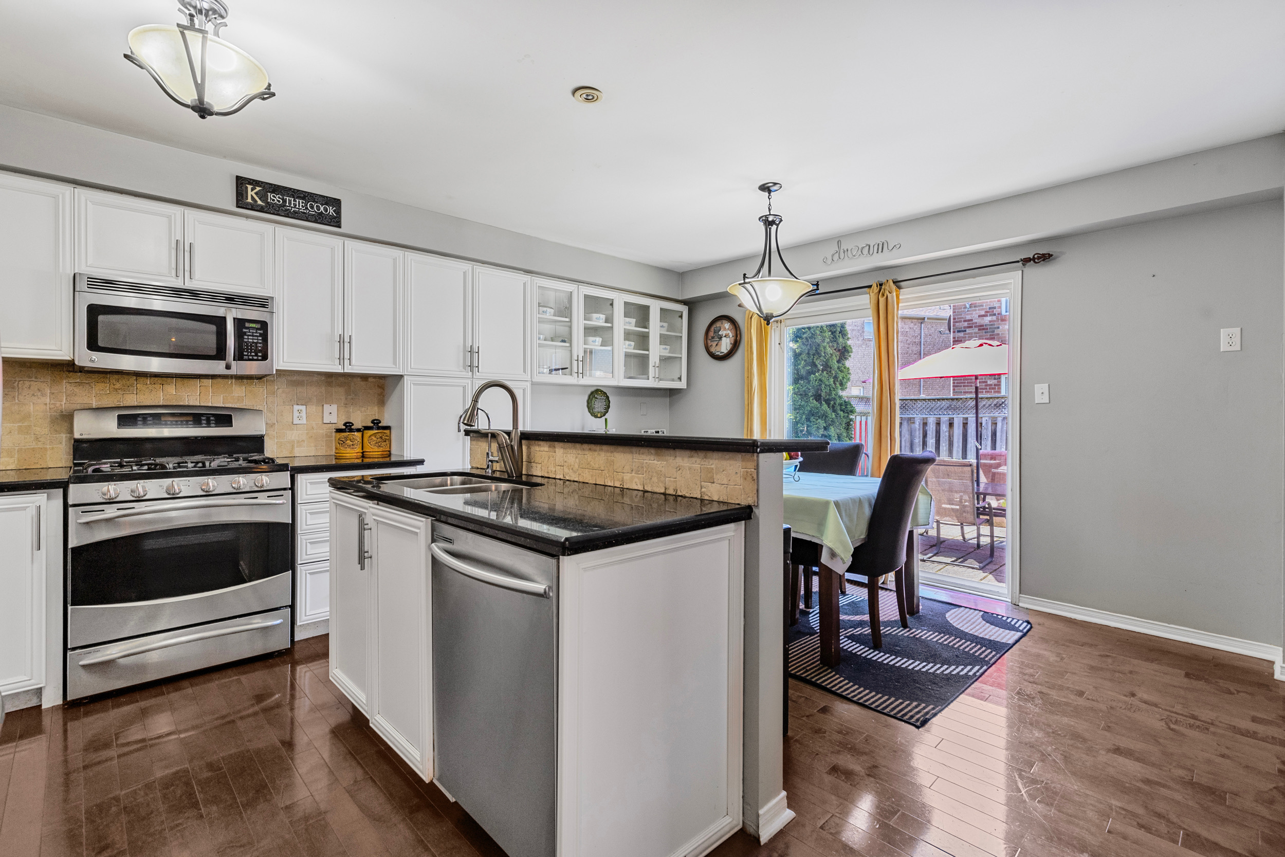 Kitchen and dining area with white cabinetry and stainless appliances