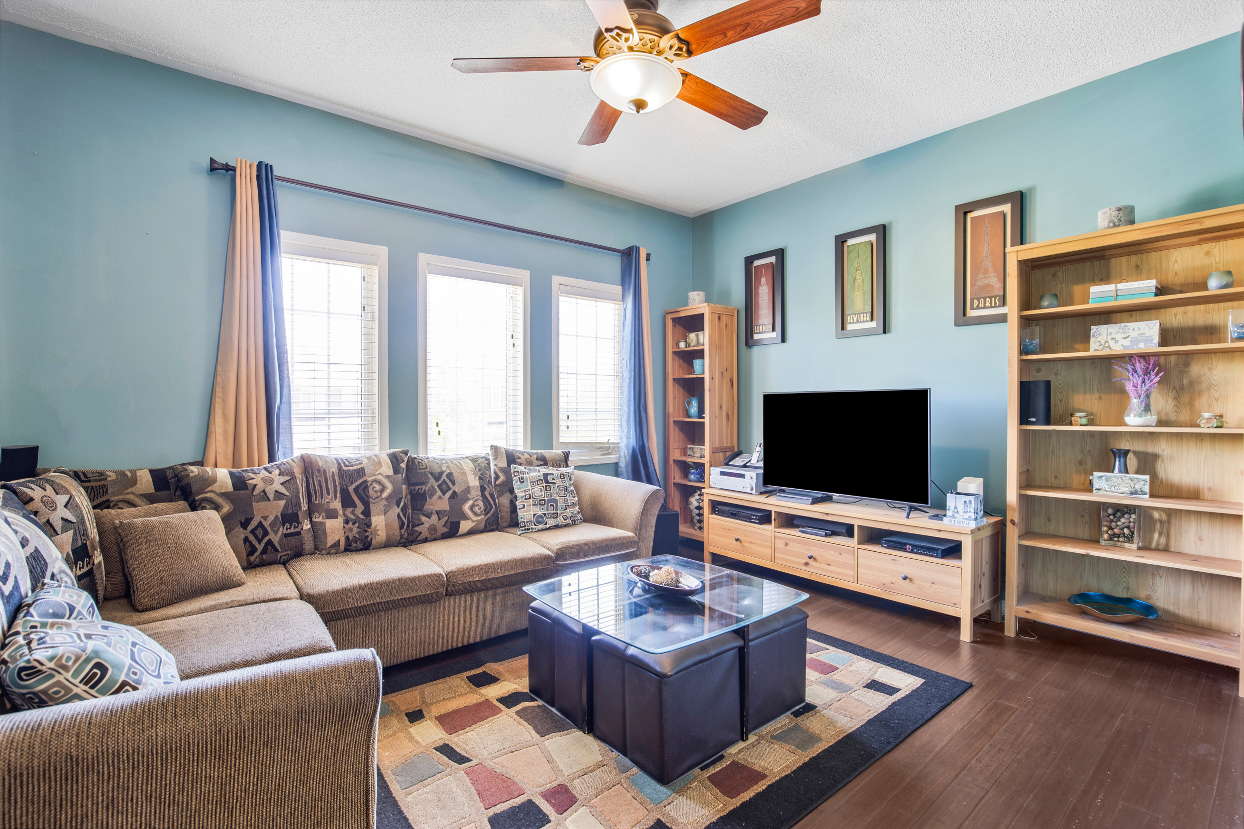 Living room with blue walls, large windows, and hardwood floors