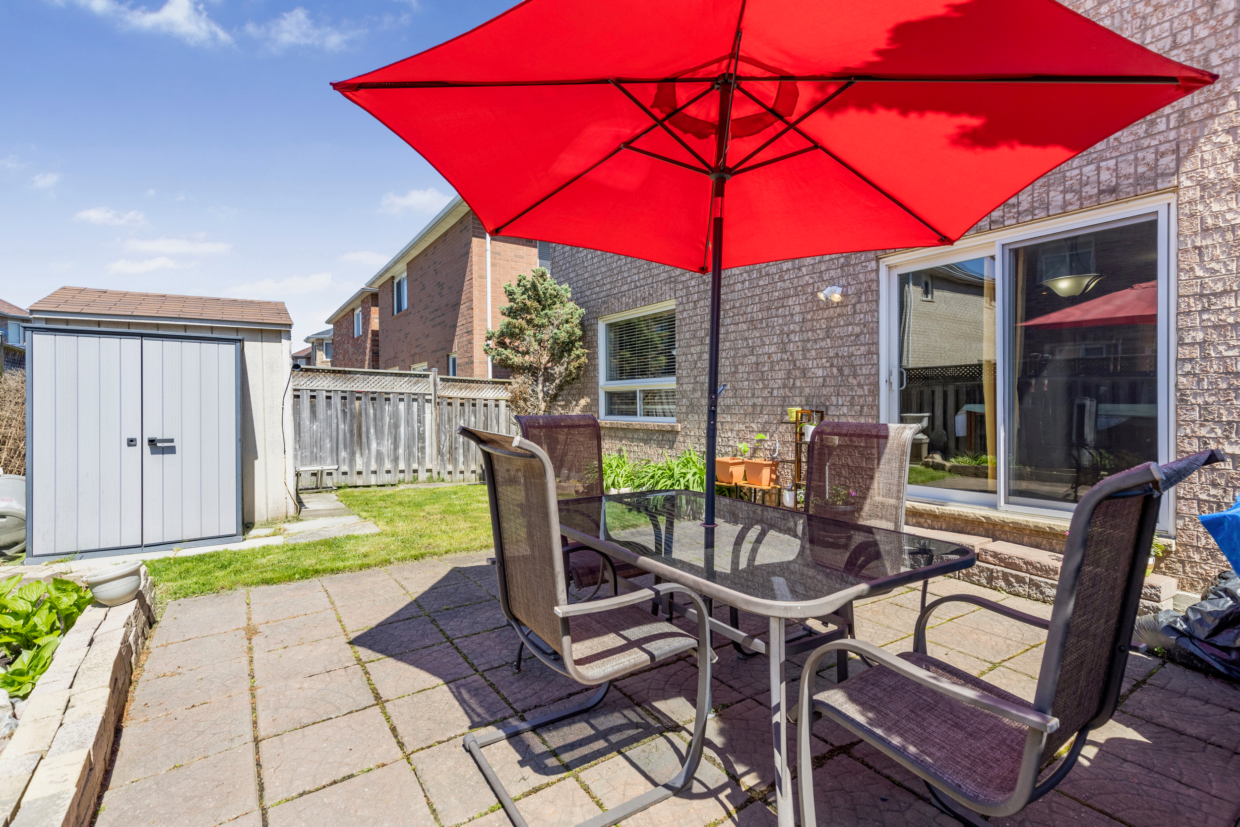 Backyard patio with outdoor dining set and red umbrella