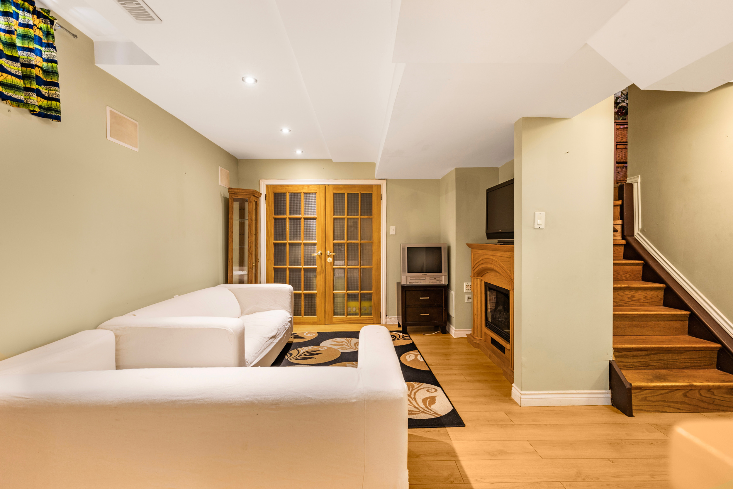Finished basement living area with laminate flooring and recessed lighting