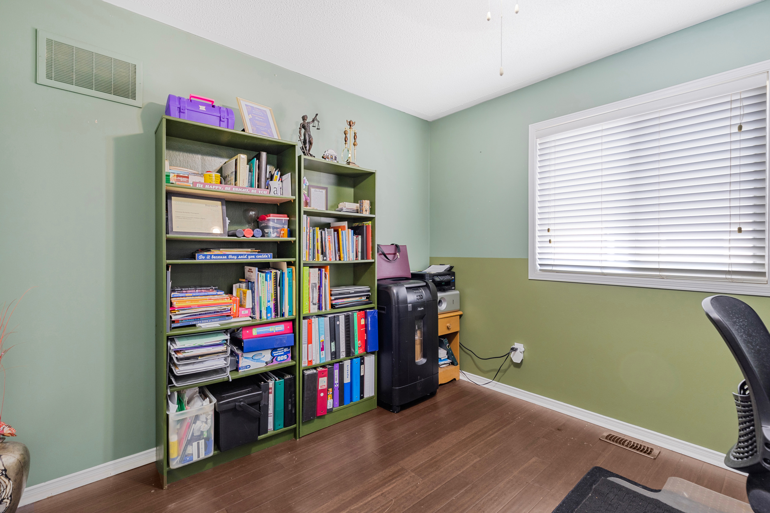 Bedroom or office with green walls and laminate flooring