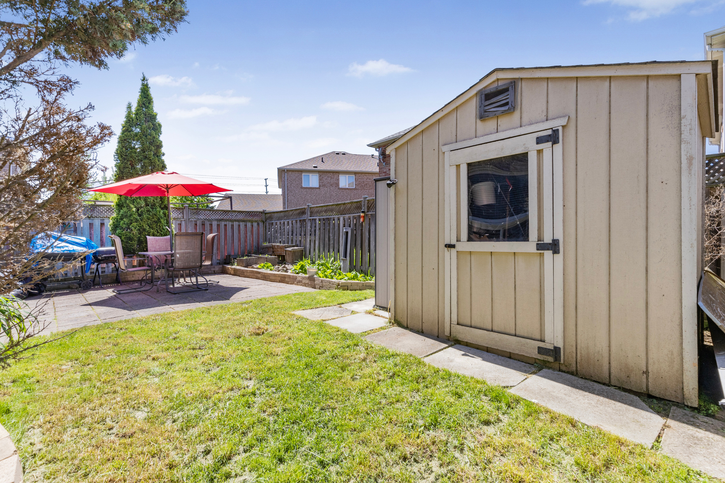 Backyard with storage shed, grass lawn, and stone patio