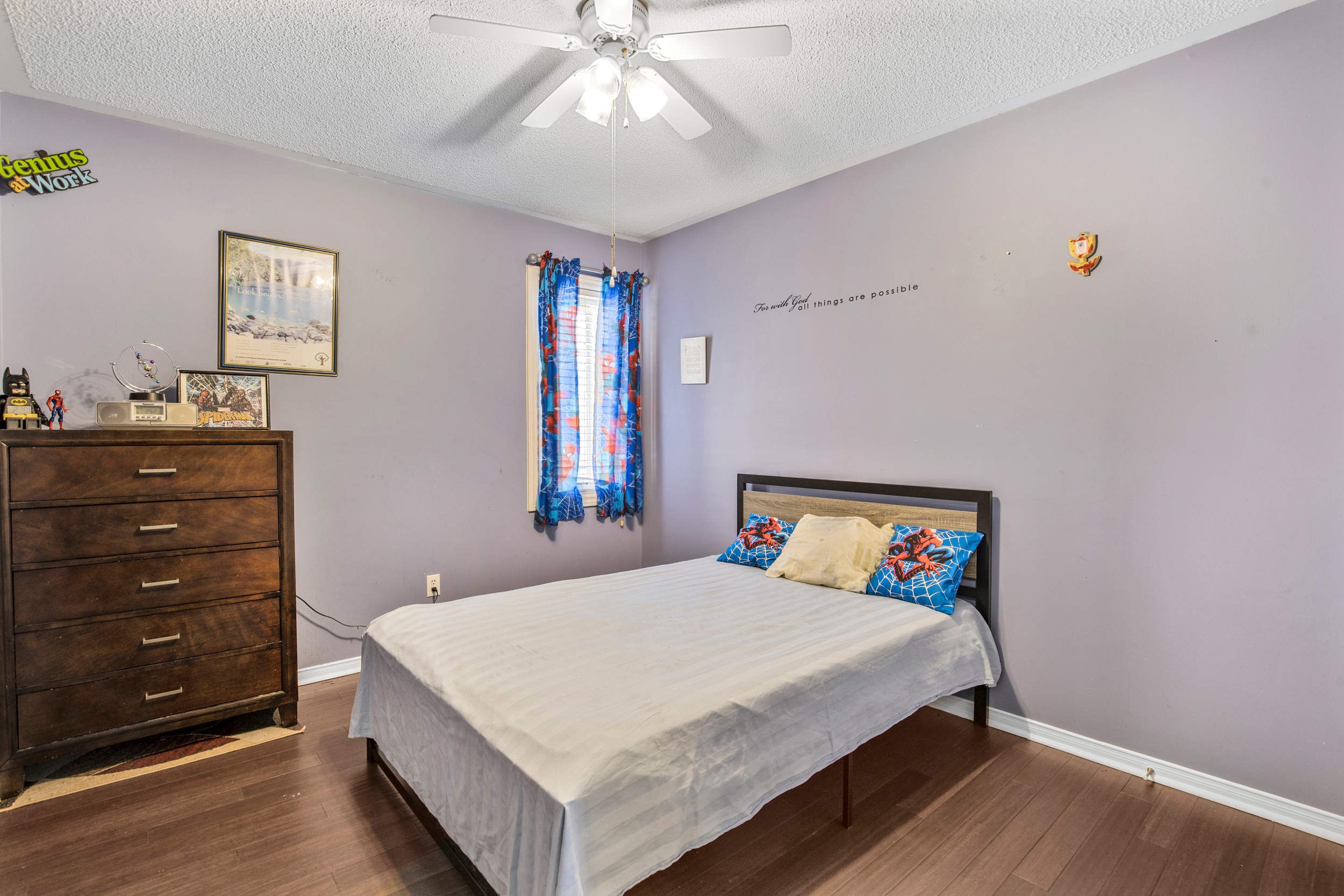 Secondary bedroom with lavender walls and laminate flooring