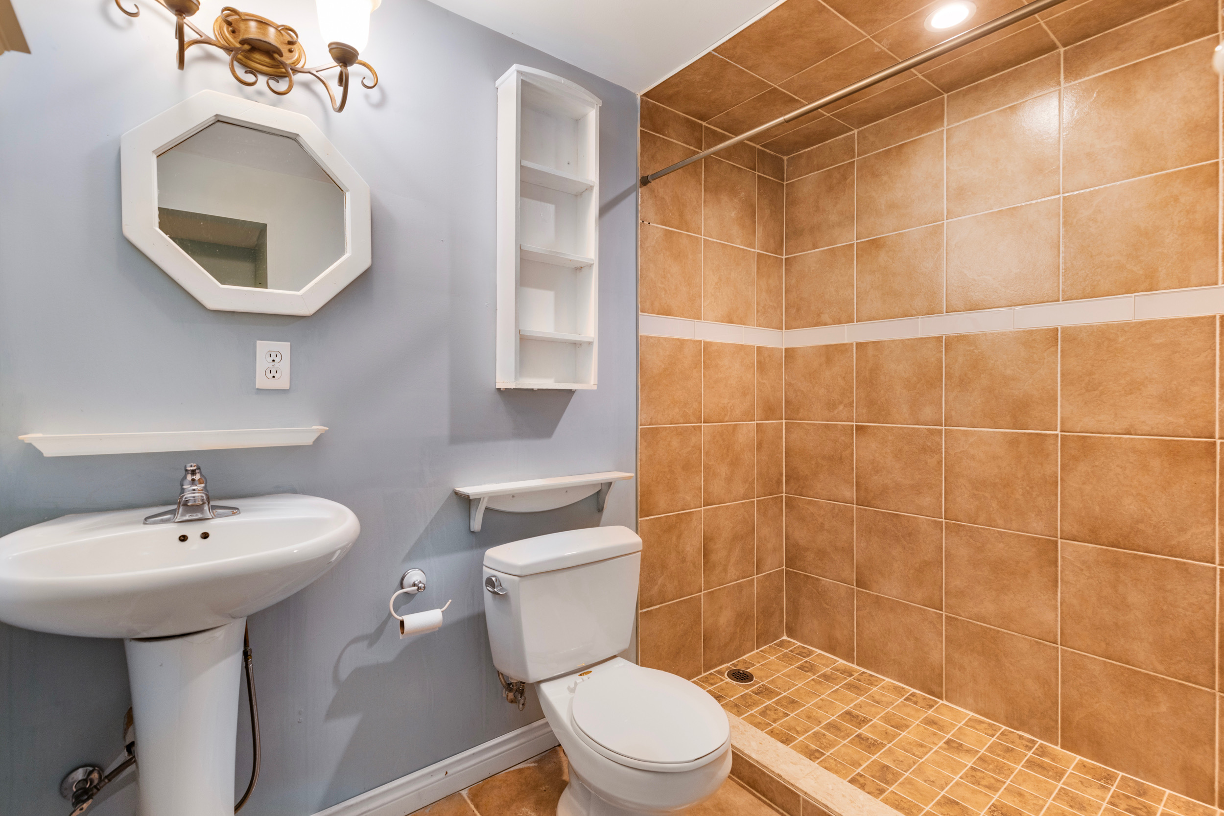 Bathroom with pedestal sink and tiled shower stall