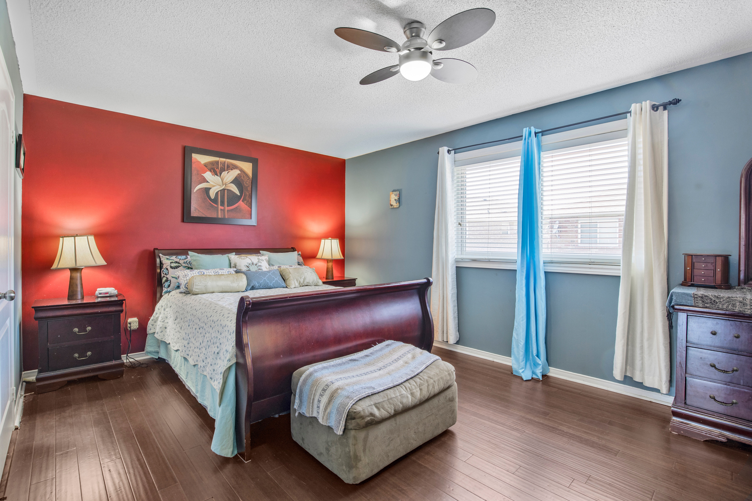 Primary bedroom with sleigh bed and red accent wall