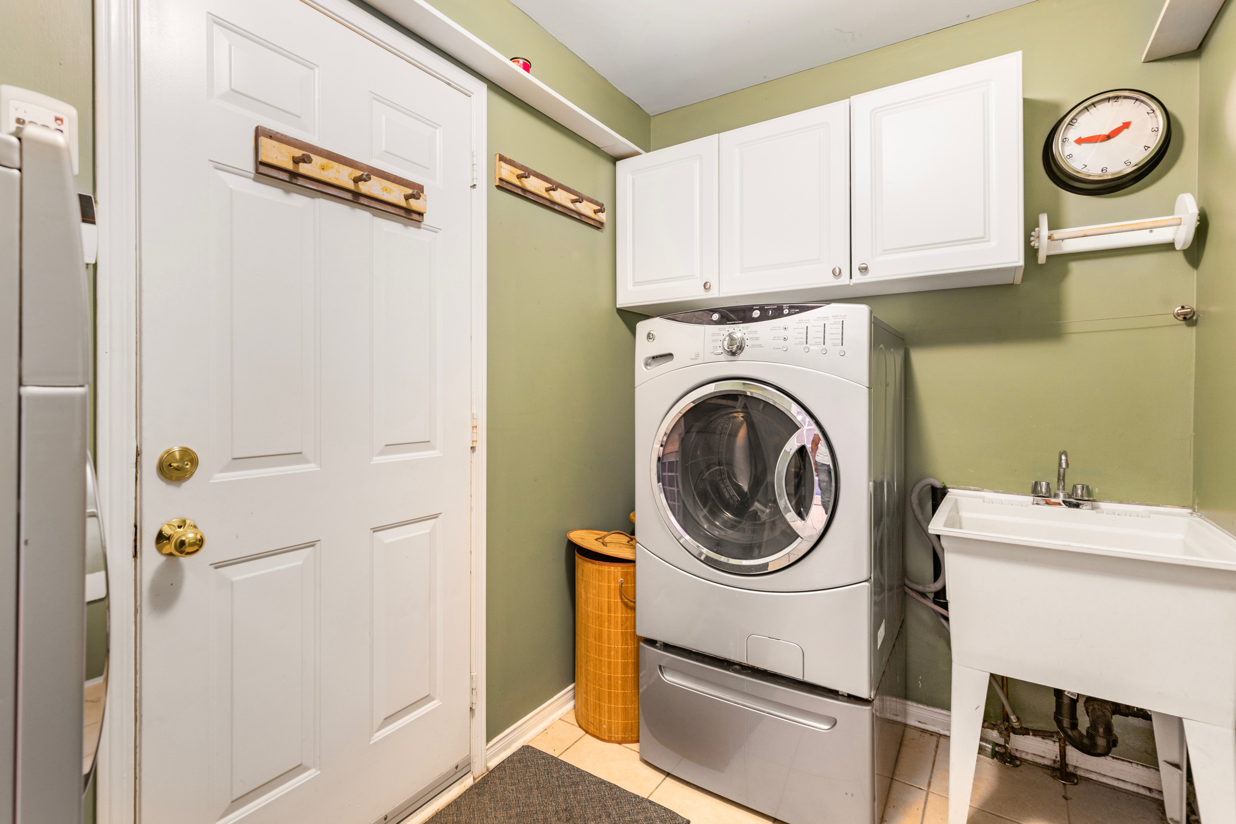 Laundry and utility room with sage green walls and white cabinetry