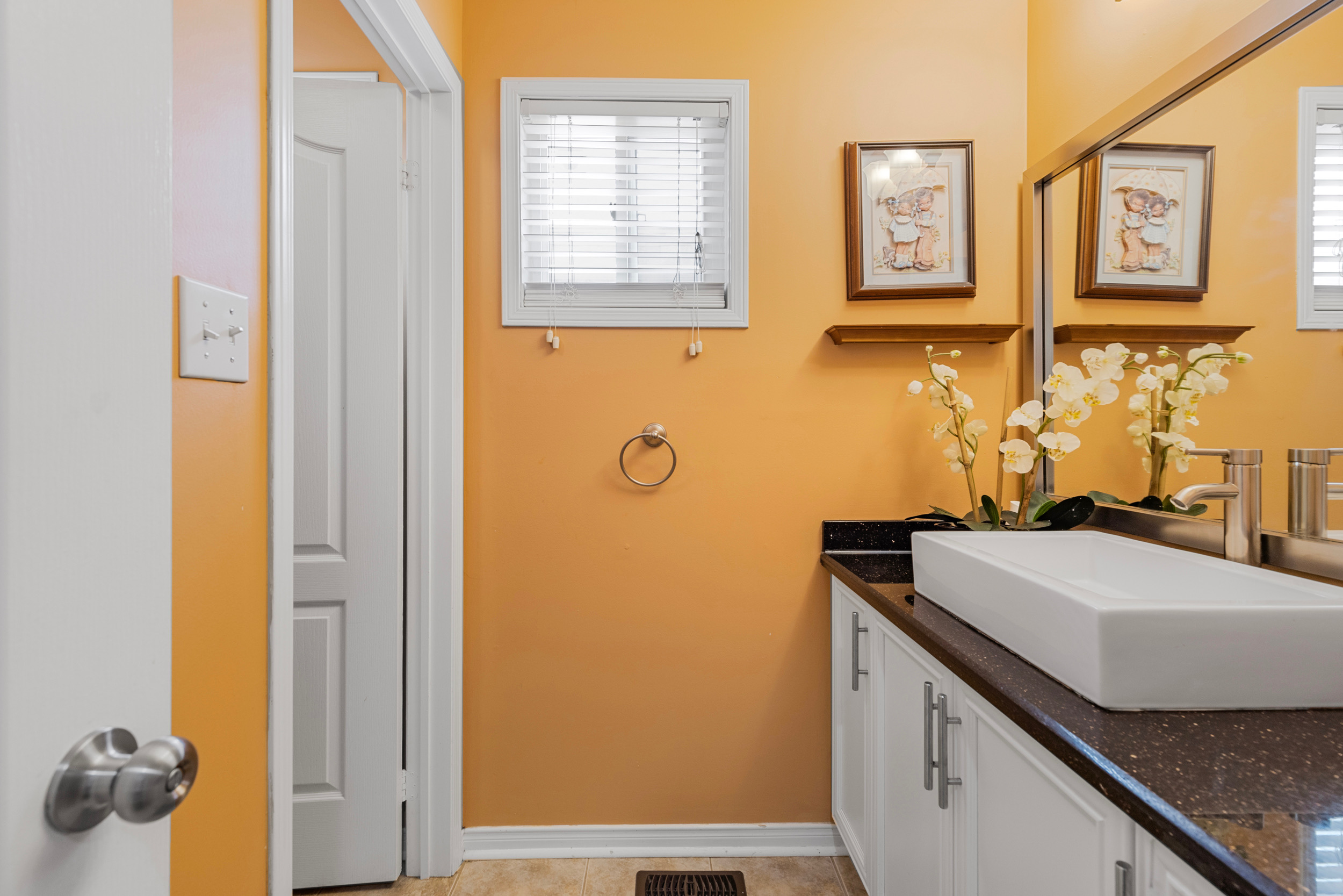 Powder room with orange accent walls and white vanity