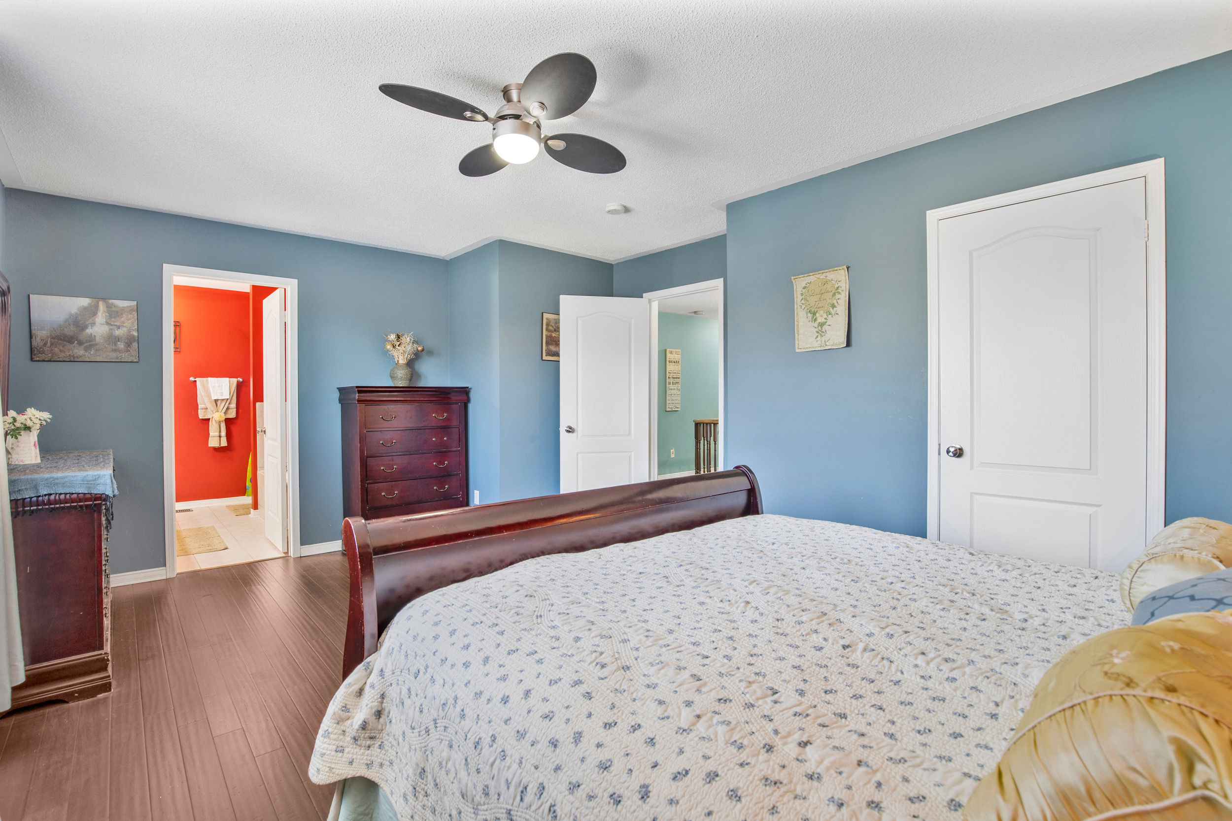 Primary bedroom with blue walls and dark wood flooring
