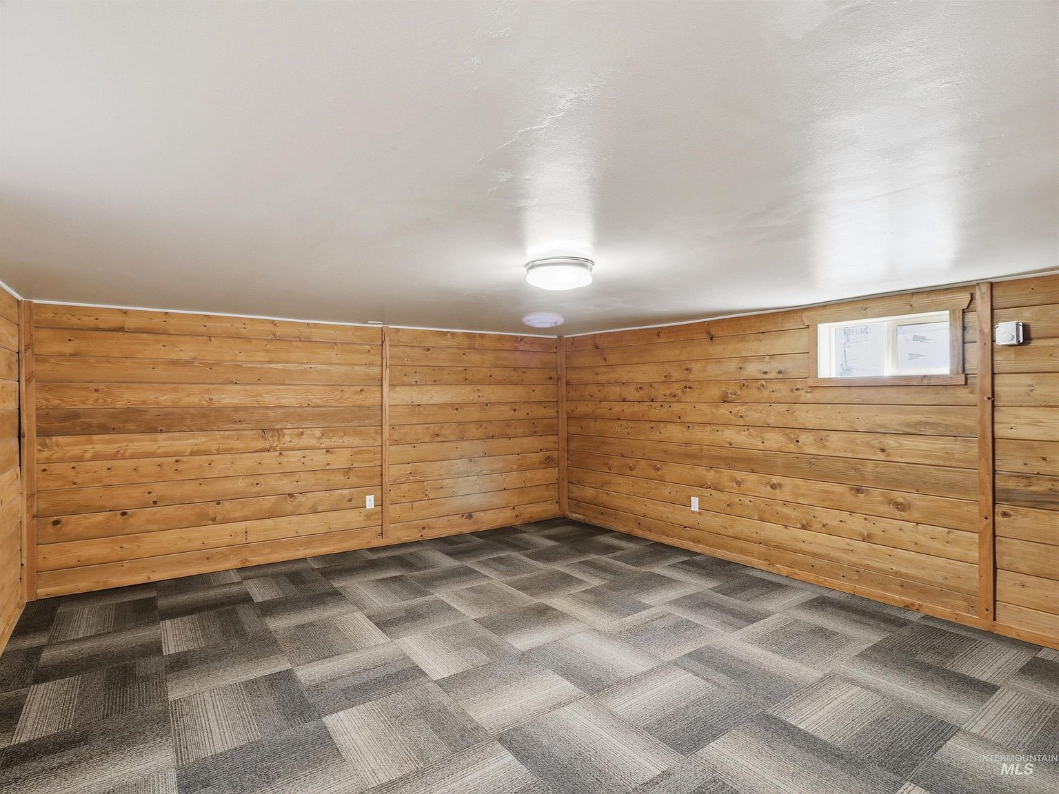 Finished basement room with wood paneling and checkerboard flooring