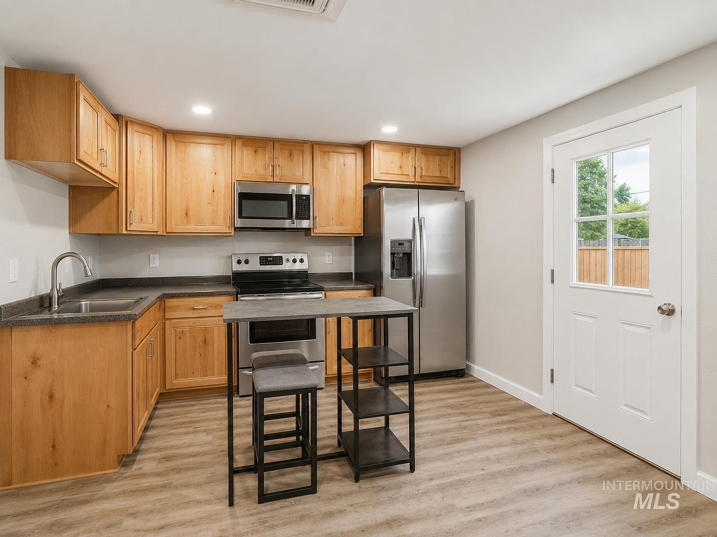 Guest house kitchen with natural wood shaker cabinets and stainless appliances