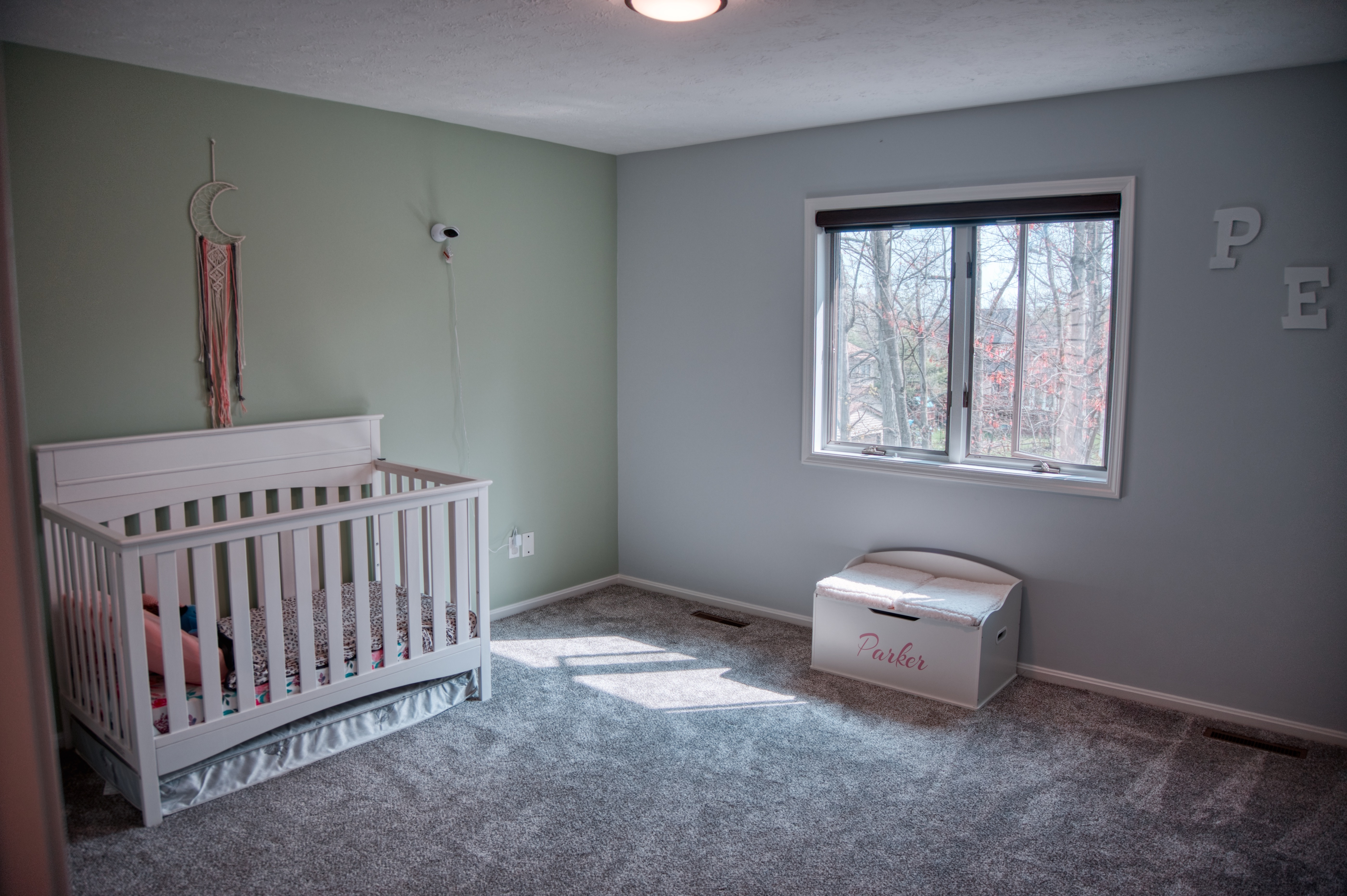 Nursery bedroom with pale green accent wall and light blue walls