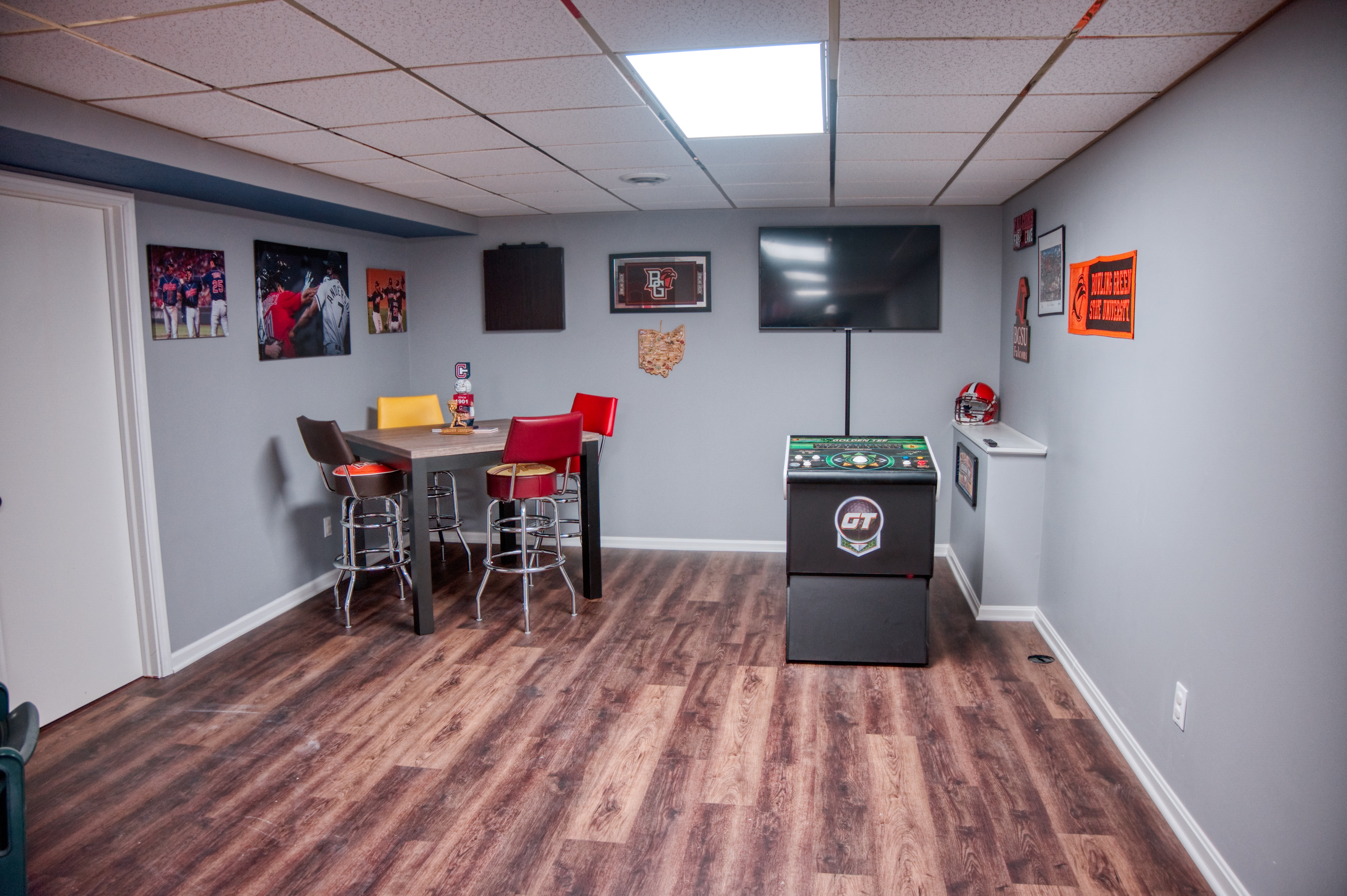 Finished basement recreation room with vinyl plank flooring and recessed lighting