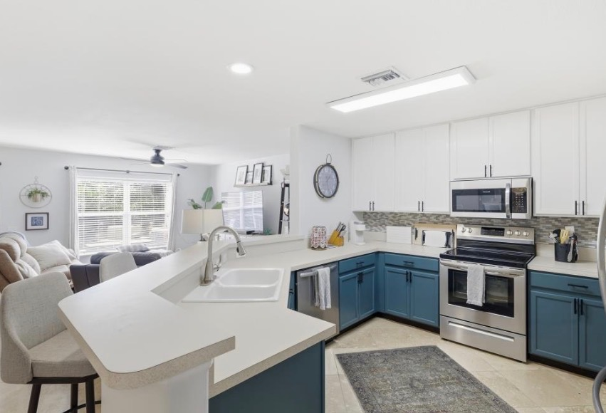 Designer kitchen with white and blue cabinetry opening to the living room at 15150 Piping Plover Ct #103