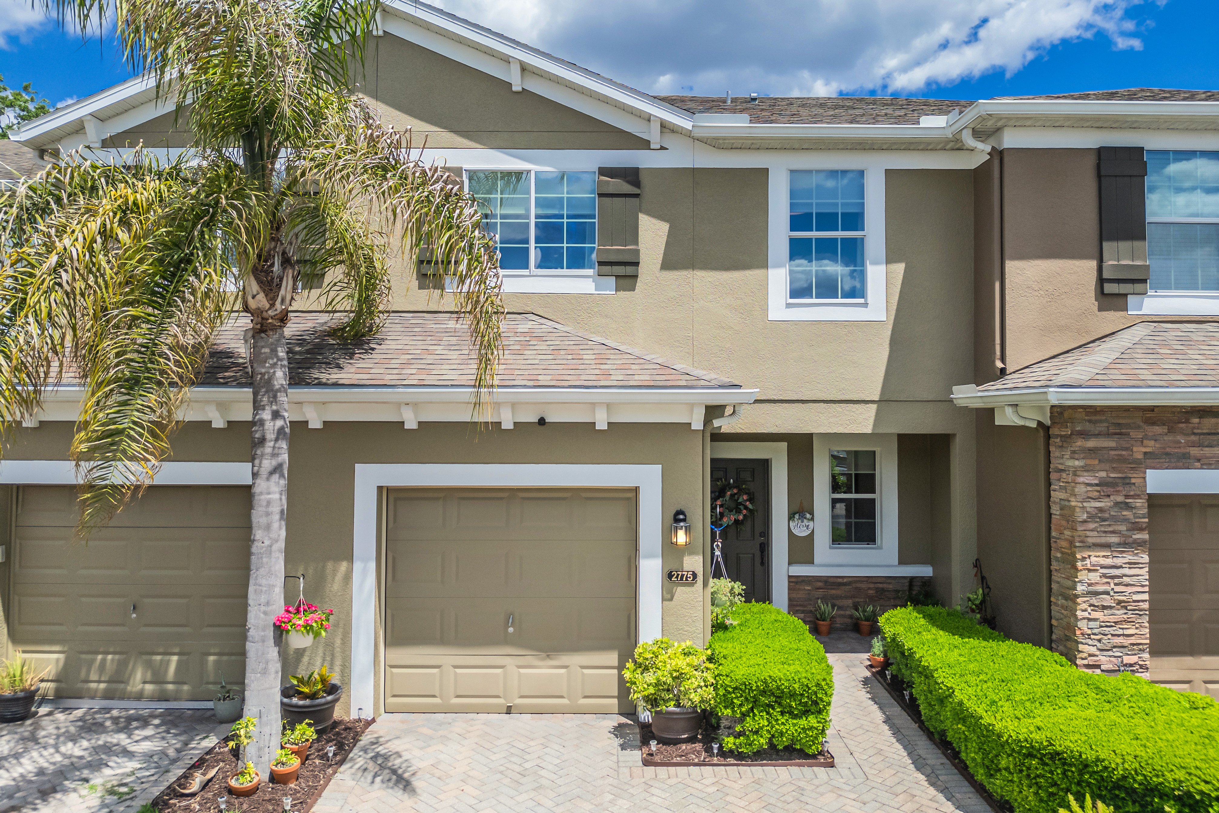 Exterior view of 2775 River Landing Dr, a two-story townhouse with tan stucco, white trim, and stone veneer accents in Sanford FL
