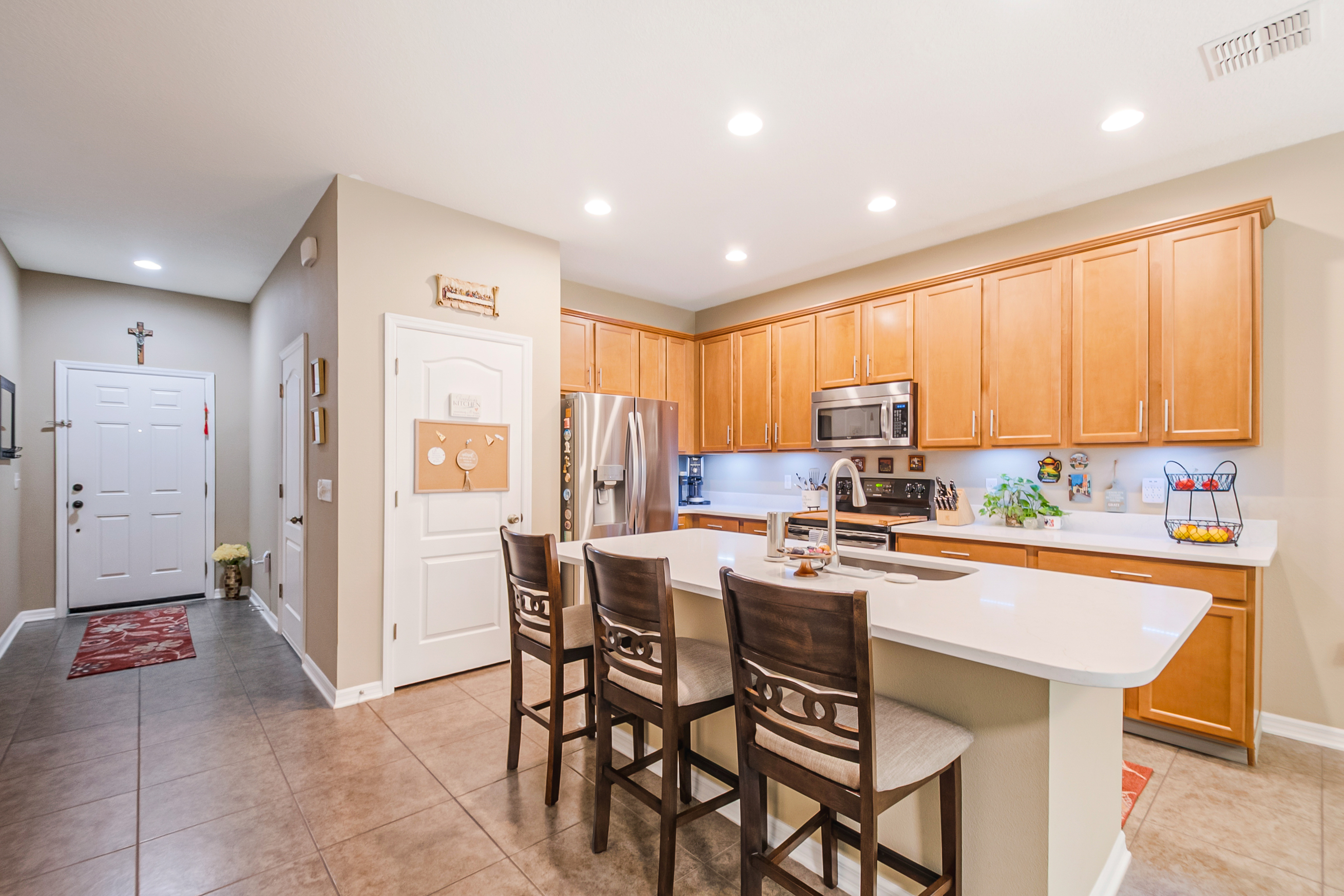 Kitchen opening to foyer with maple cabinetry and white quartz countertops