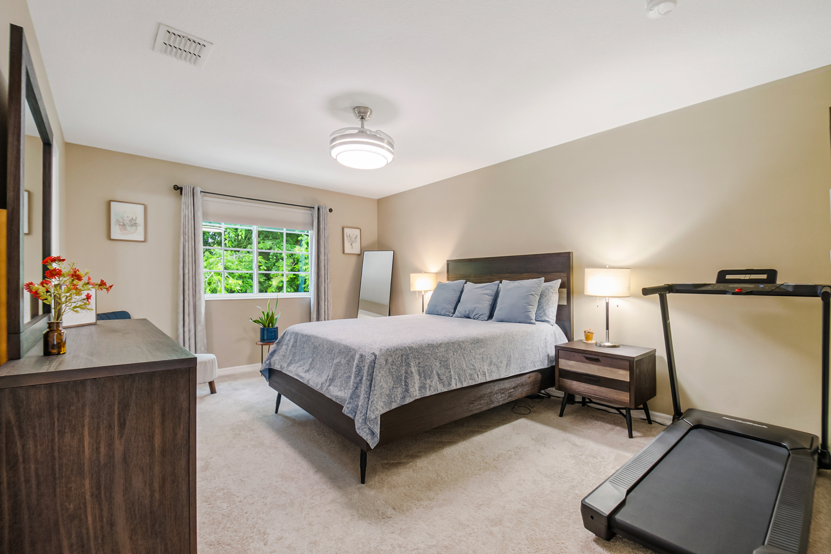 Master bedroom with neutral beige walls, carpeted floors, and natural light