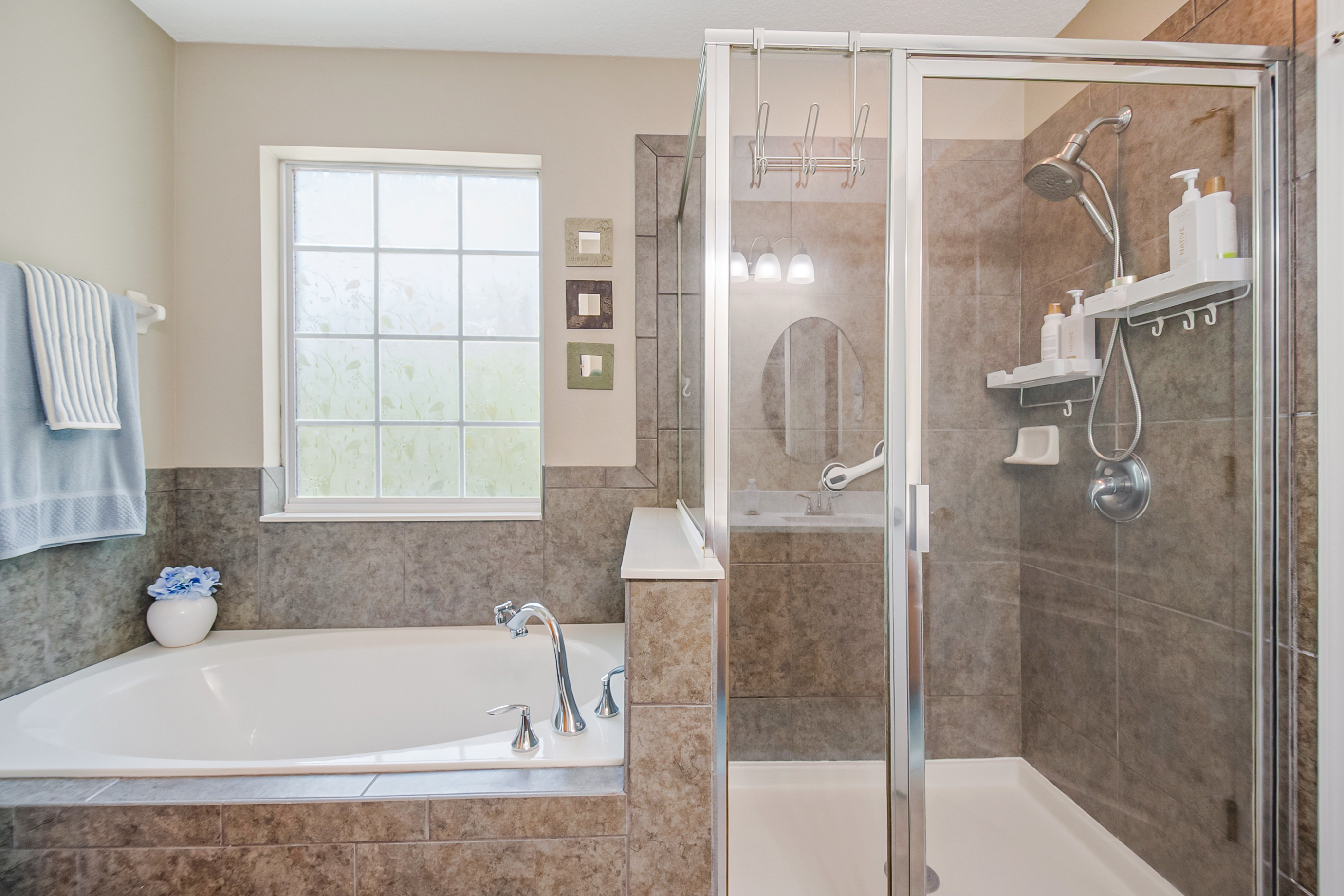 Primary en suite bathroom with soaking tub and glass-enclosed shower