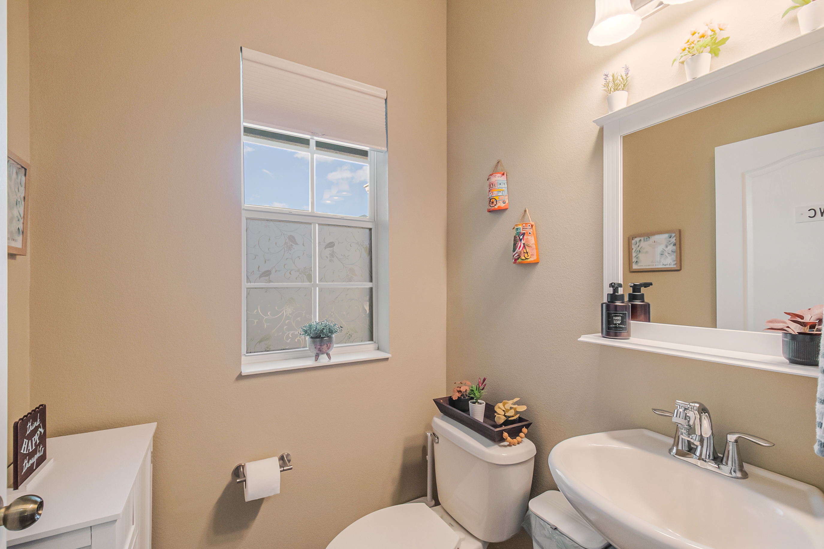 Half bathroom or powder room with neutral tan paint and white fixtures