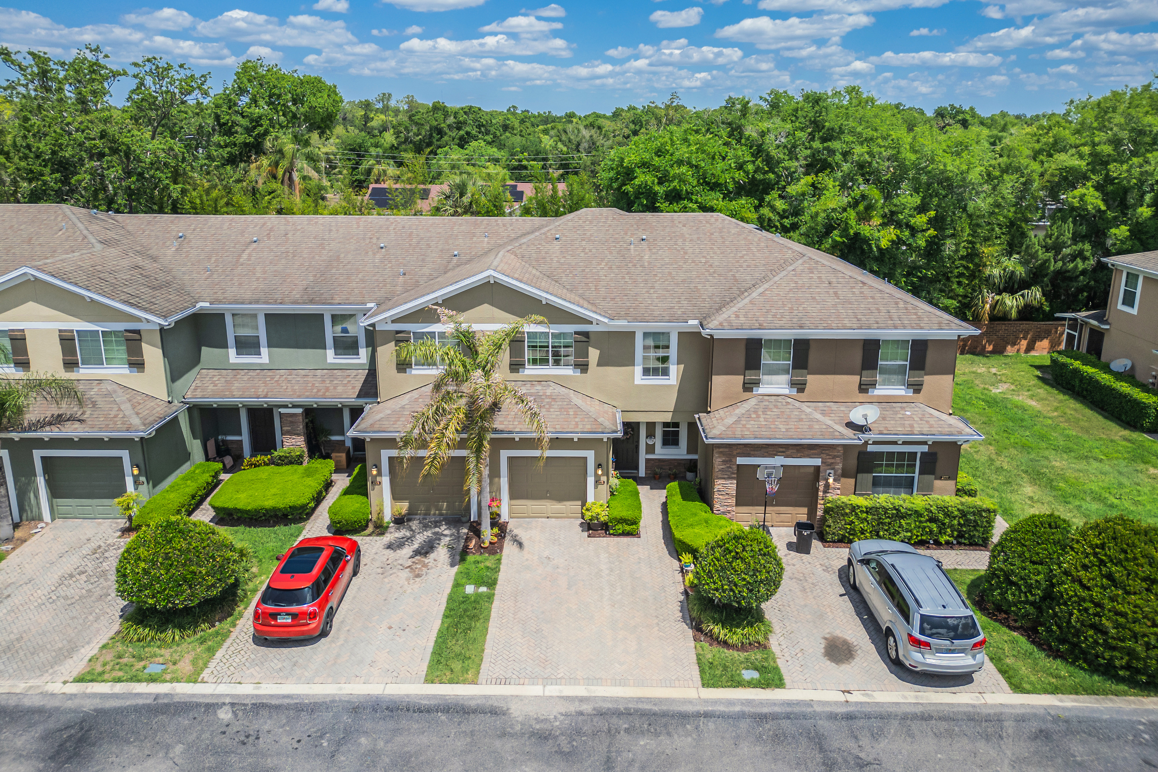 Aerial drone view of the townhouse complex with earth-toned stucco and shingle roofing