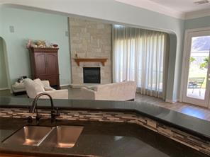 Living room with floor-to-ceiling stone fireplace, hardwood floors, and tall windows at 6106 Peachtree Hill Court