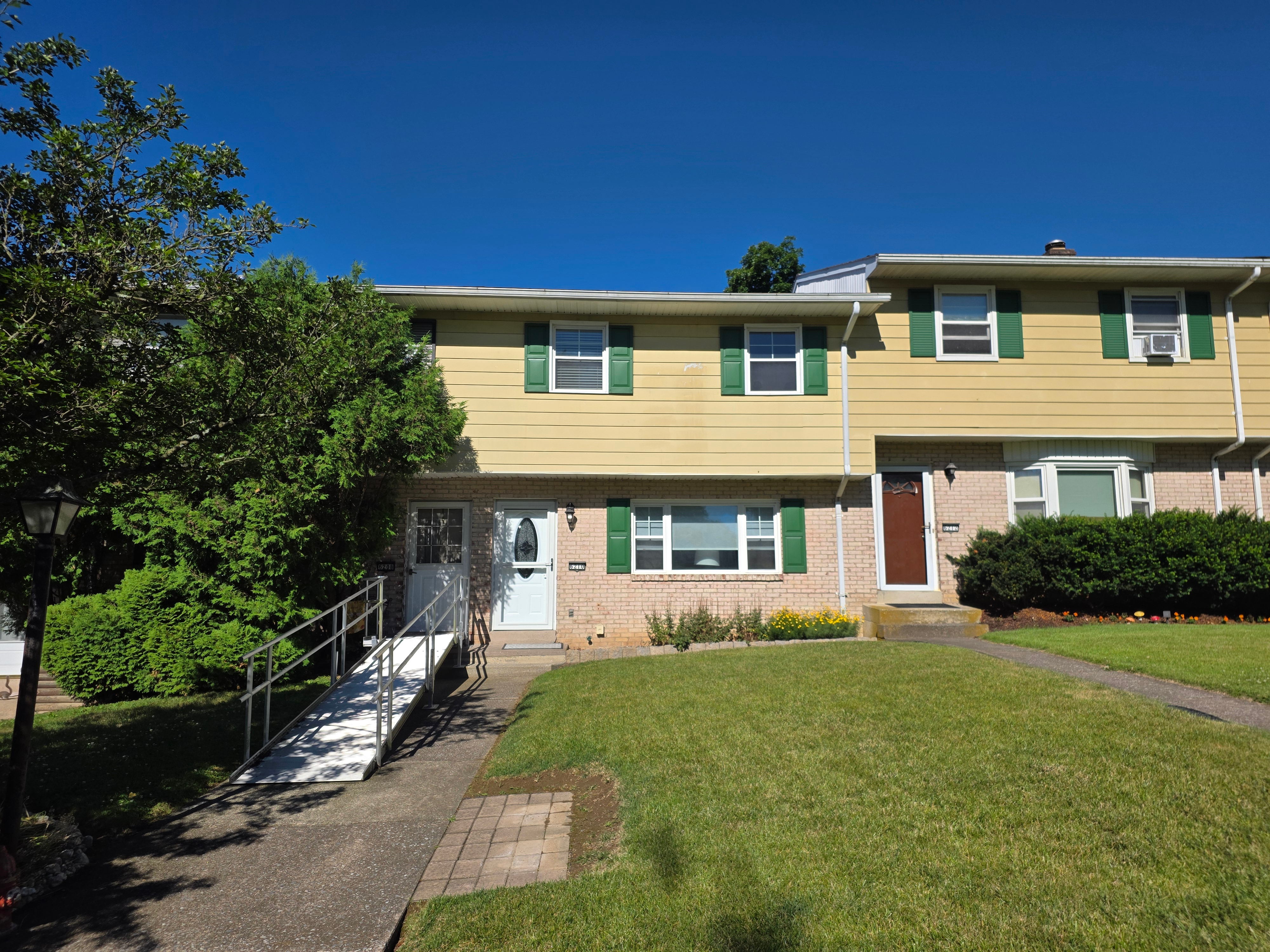 Front facade of 6210 Glen Court showing vinyl siding, brick lower level, green shutters, and concrete walkway