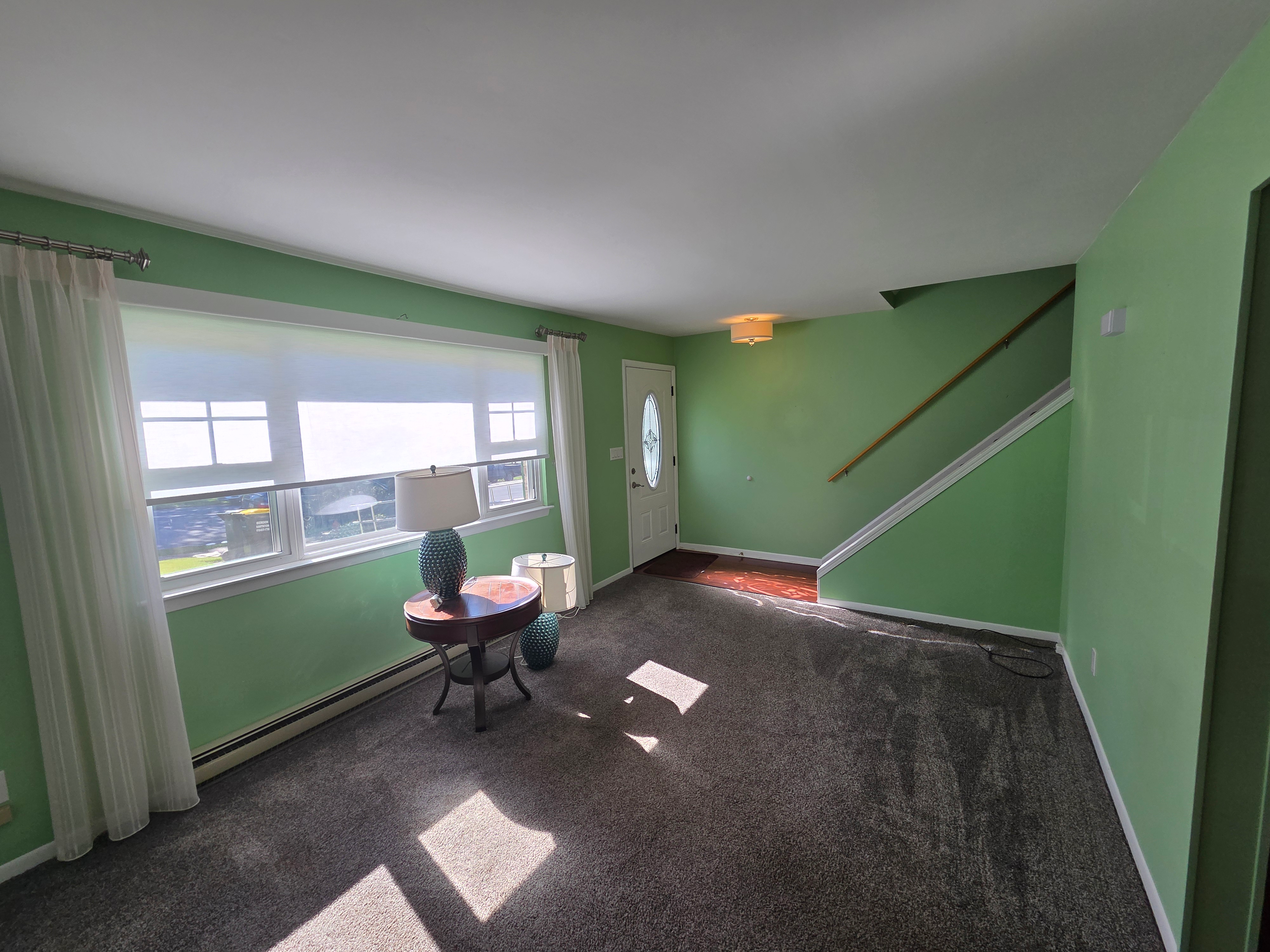 Living room with wall-to-wall carpeting, light green painted walls, and natural daylight from front window