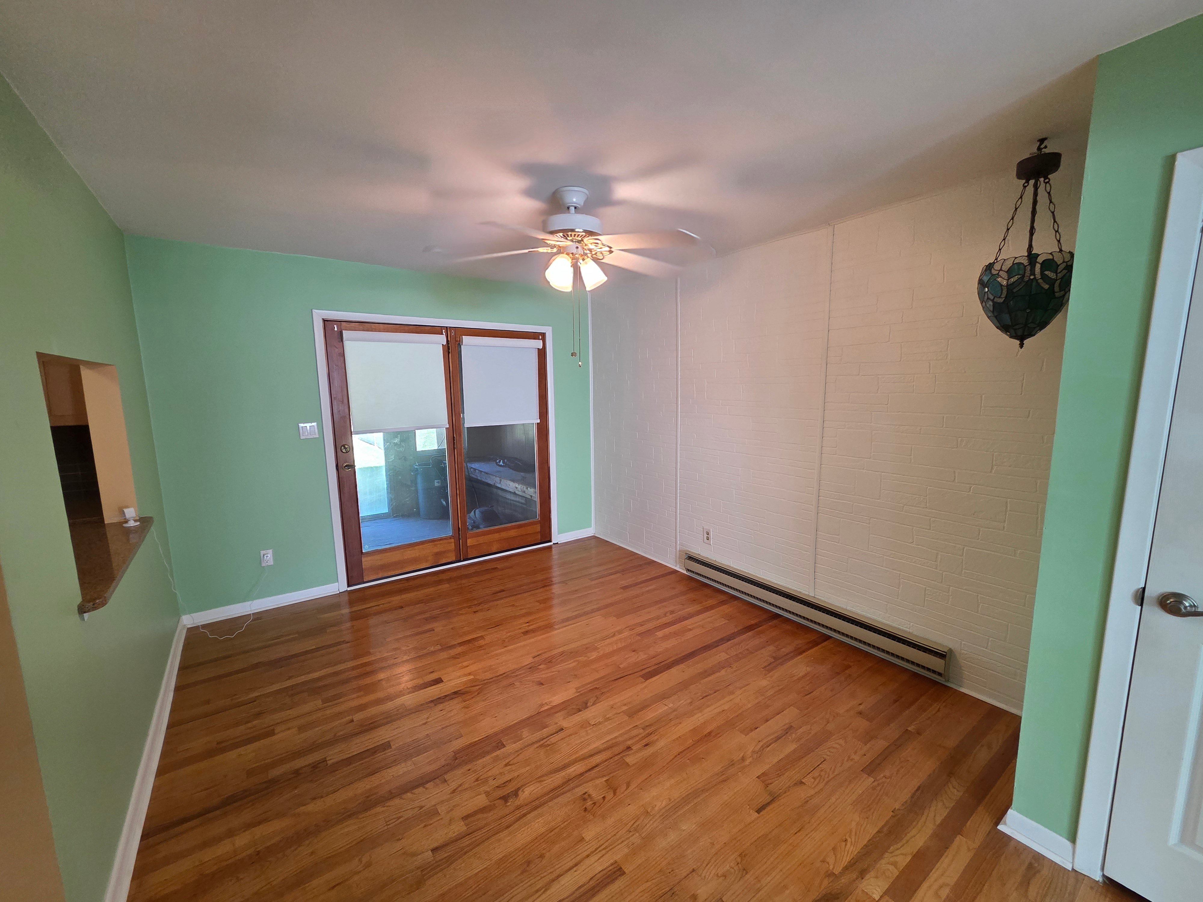 Dining room with hardwood flooring, light green walls, and sliding glass door to sun porch