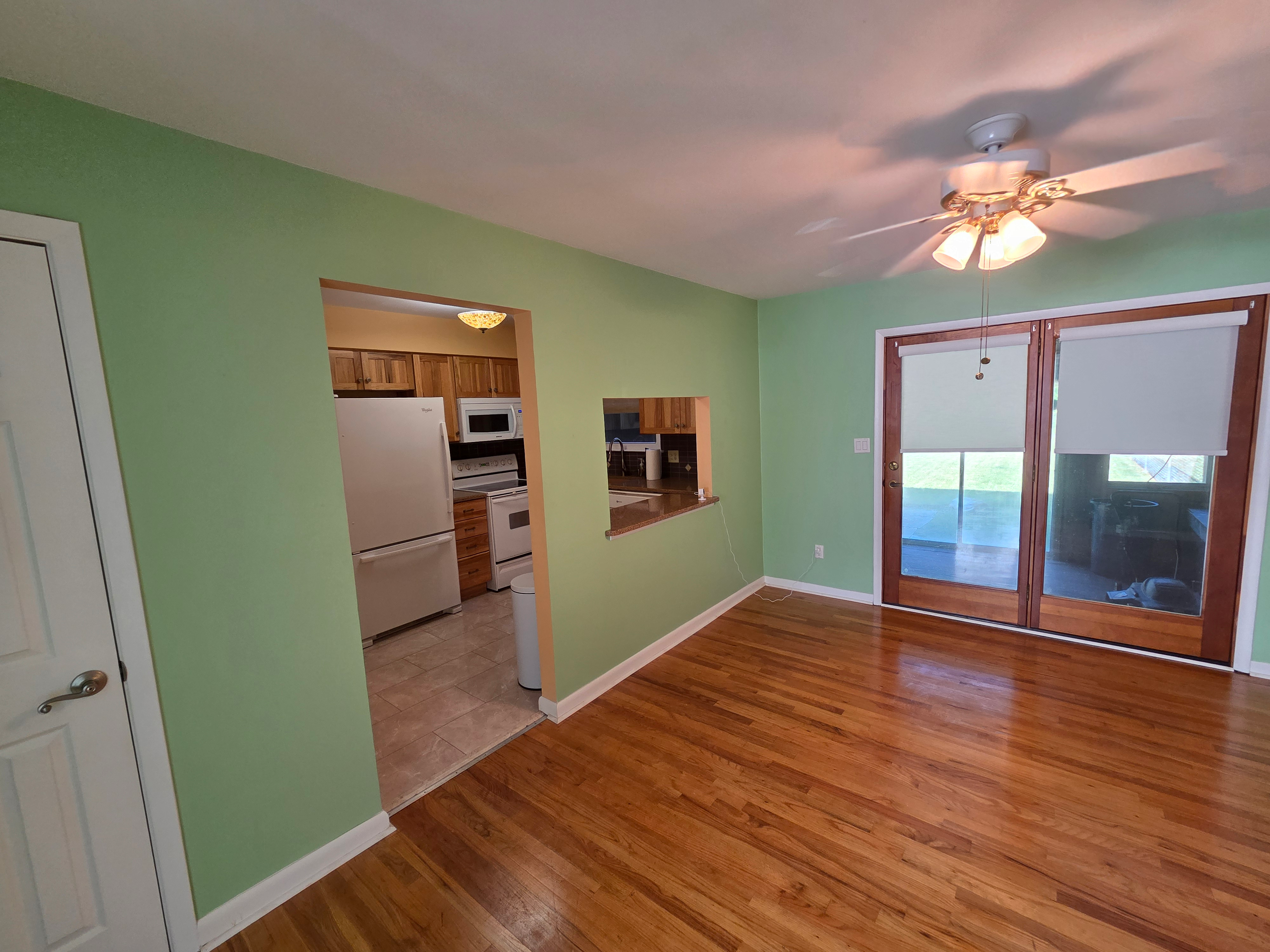 Dining room with hardwood flooring, light green walls, and sliding glass door to sun porch