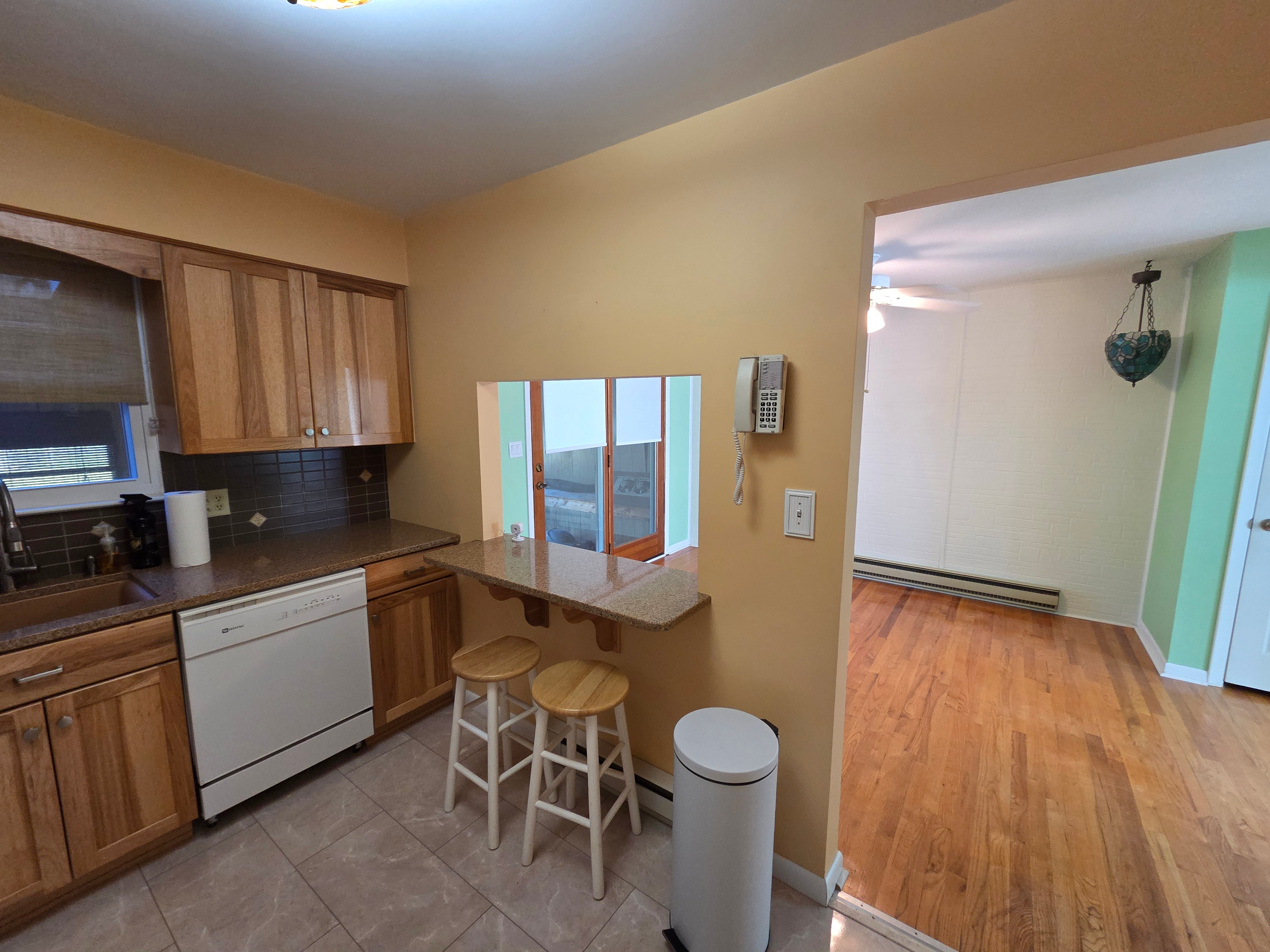 Kitchen breakfast bar pass-through to dining area with granite countertop and tile flooring