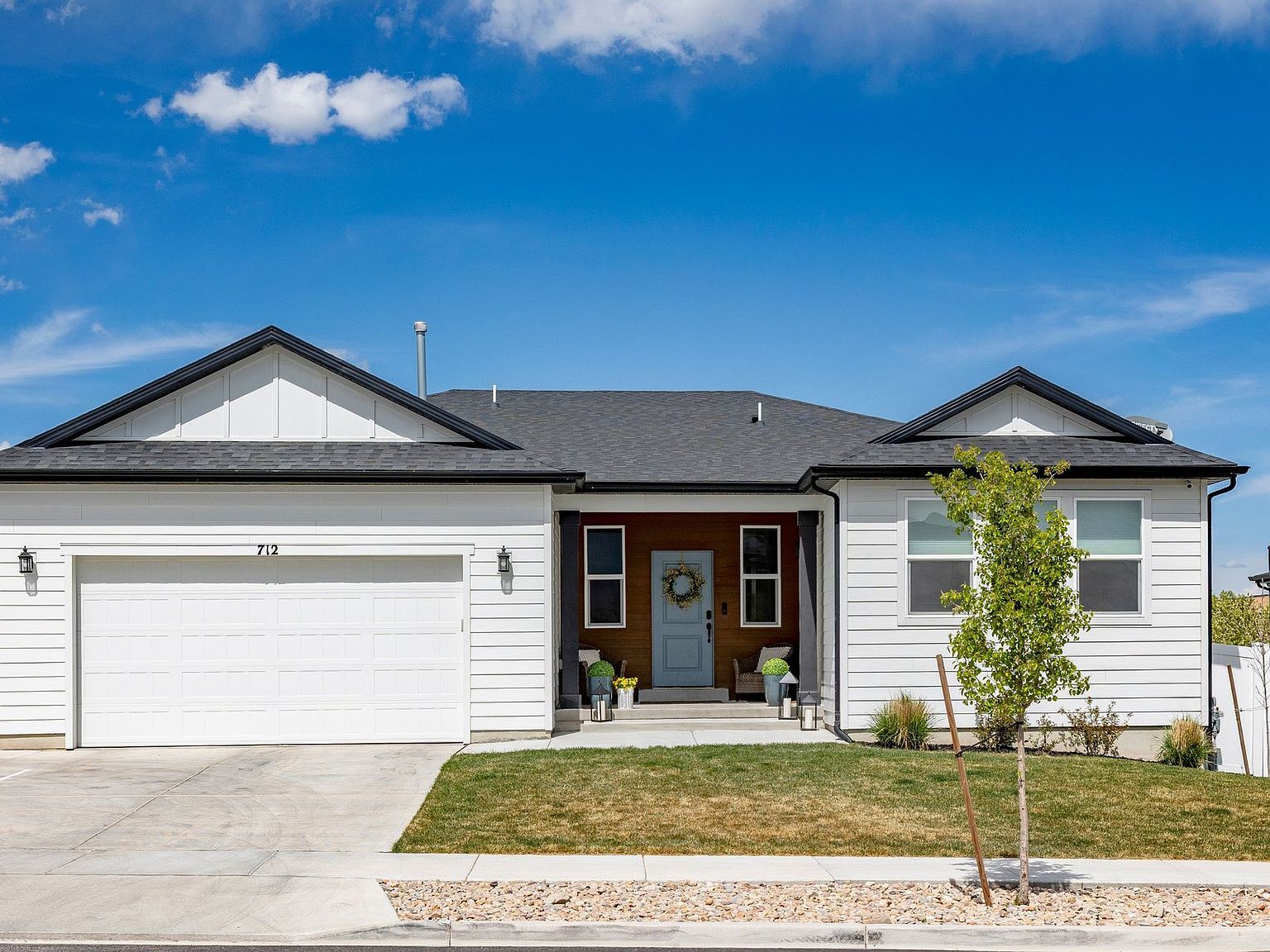Front exterior of 712 W Blue Mountain Dr, a modern white rambler with wood accent entry