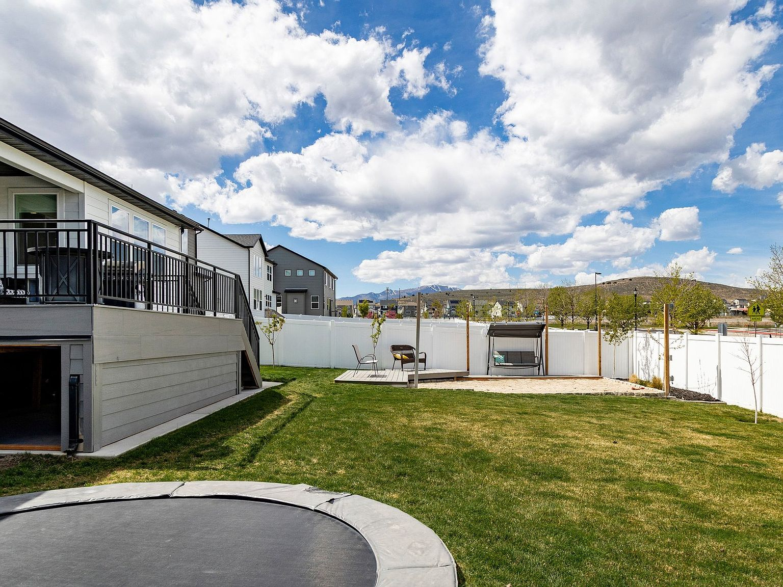 The backyard with its oversized deck, trampoline, and mountain backdrop