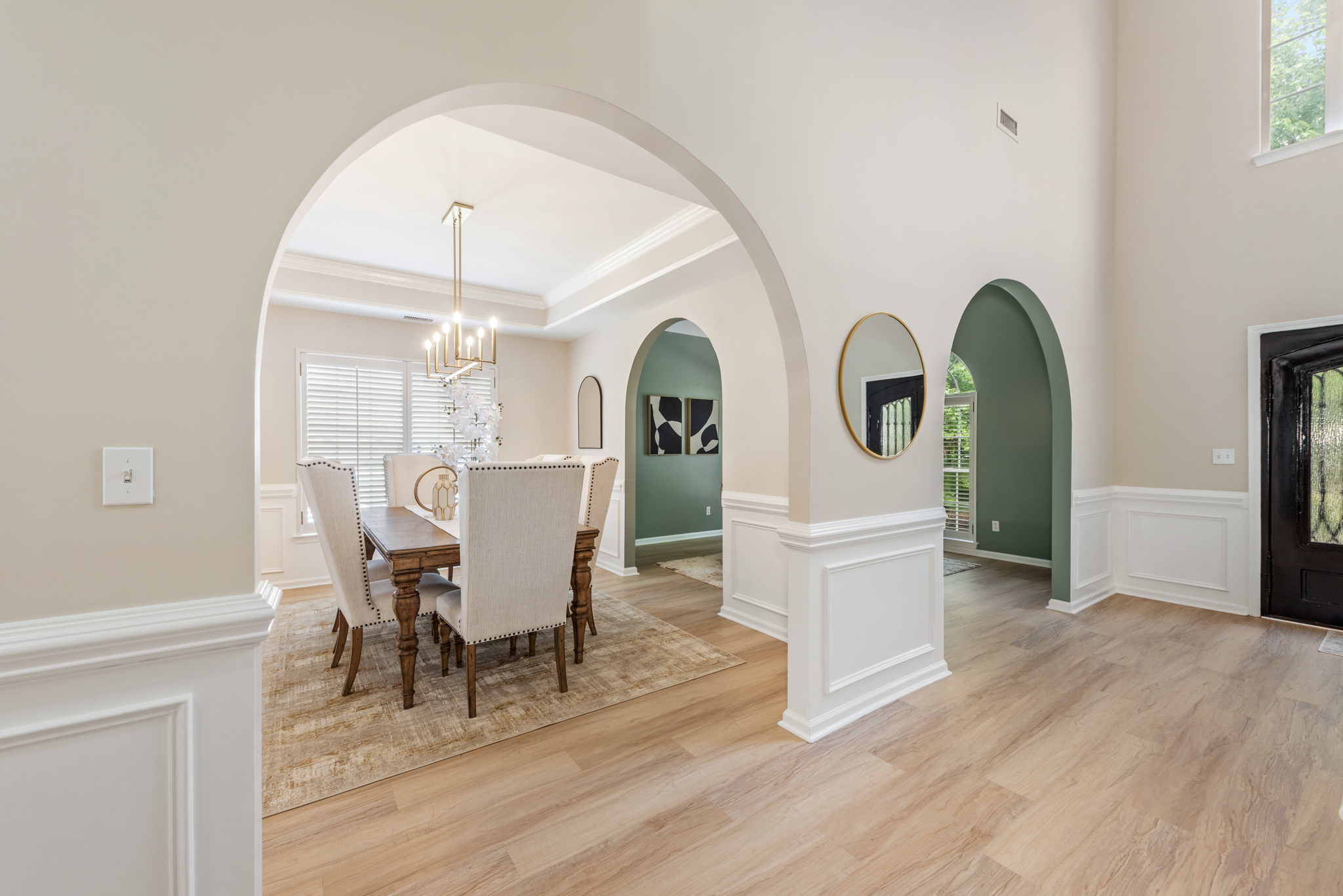 Dining room seen through architectural archways with wainscoting and soft earth tones