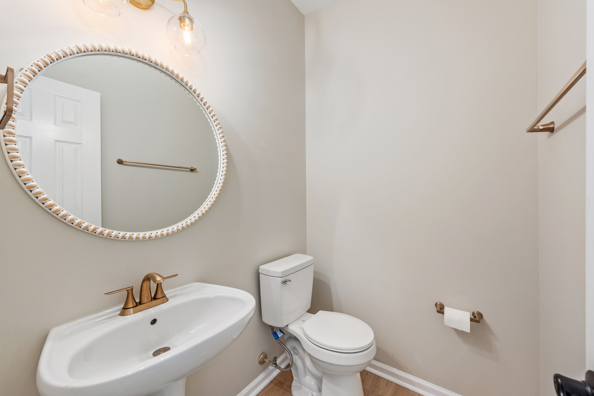 Powder room with pedestal sink, brass fixtures, and beaded-edge mirror