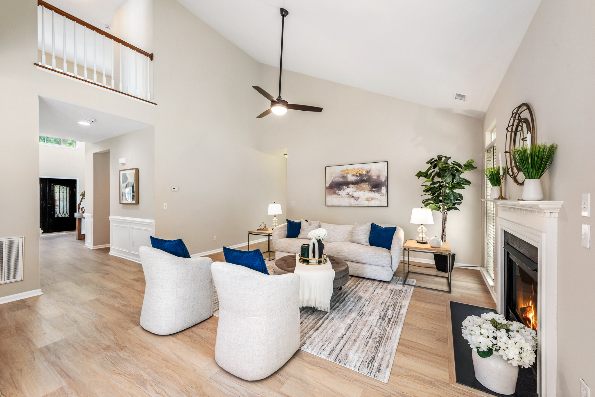 Vaulted living room with fireplace, light wood flooring, and neutral walls